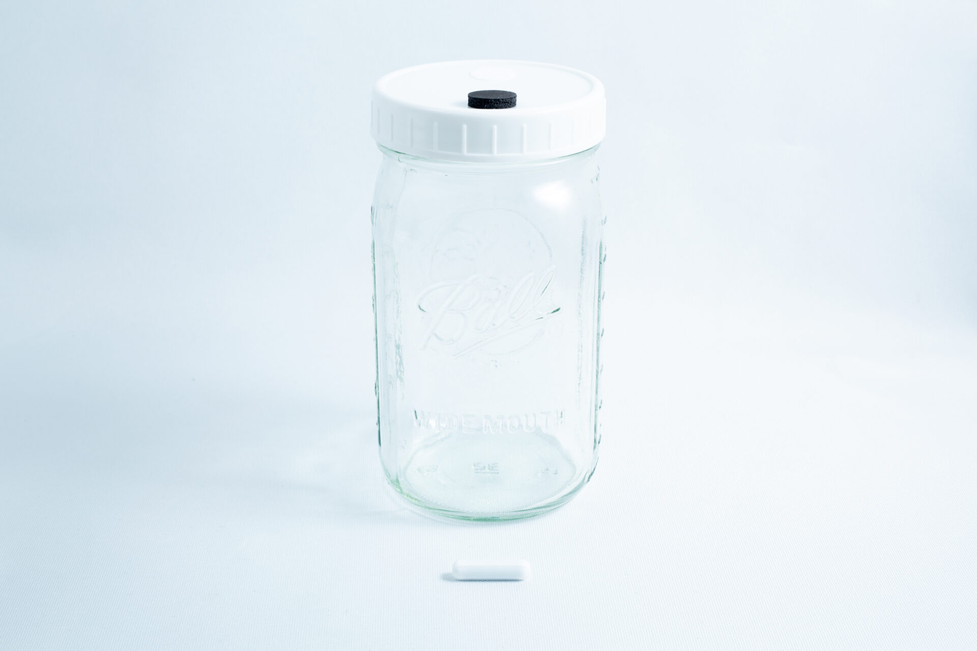 1L Mycology Ball mason jar with injection port and air vent, genuine and autoclavable, features a white lid and a small white cylindrical object in front, displayed on a white background.