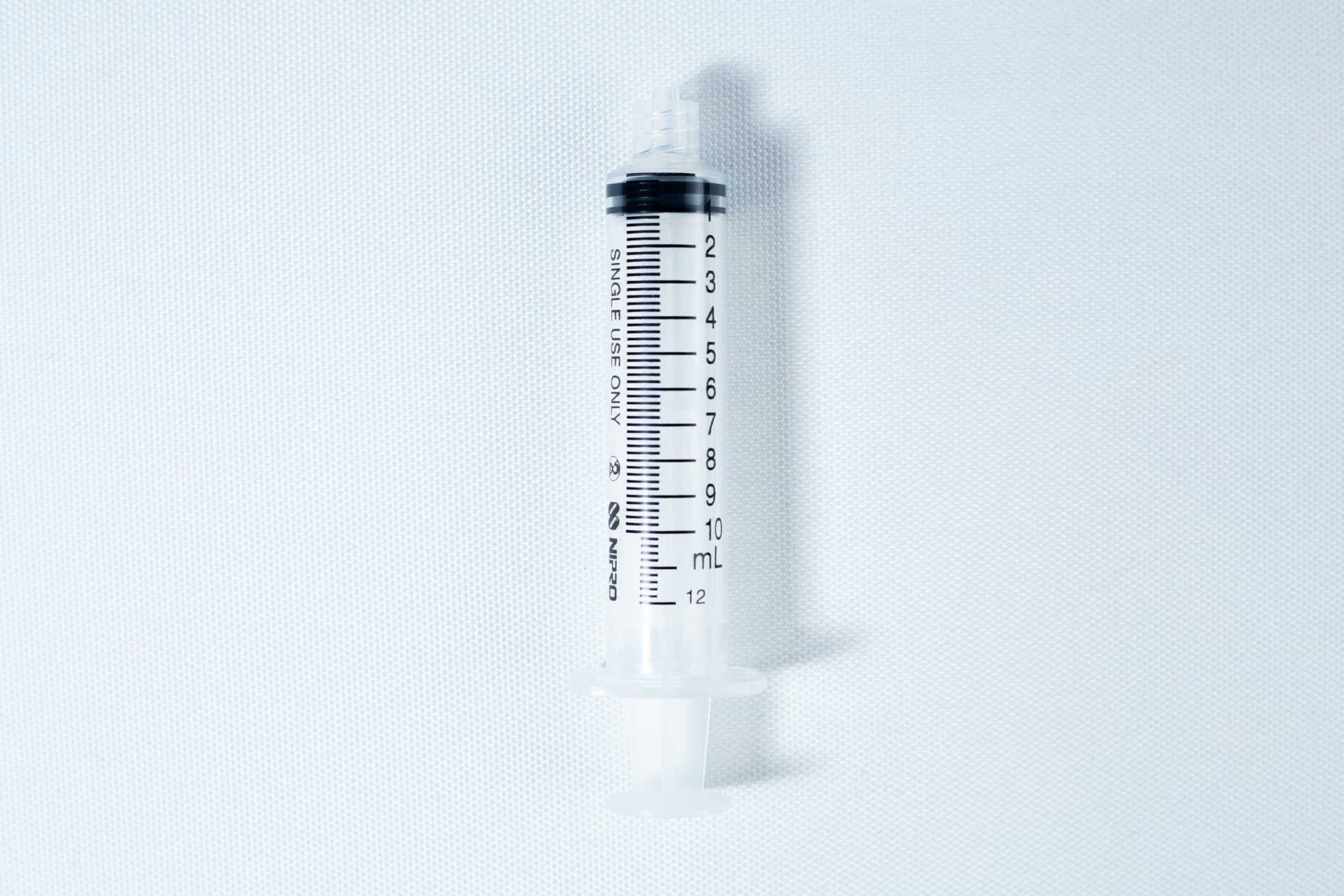 A clear plastic syringe with black measurement markings, placed on a white background.