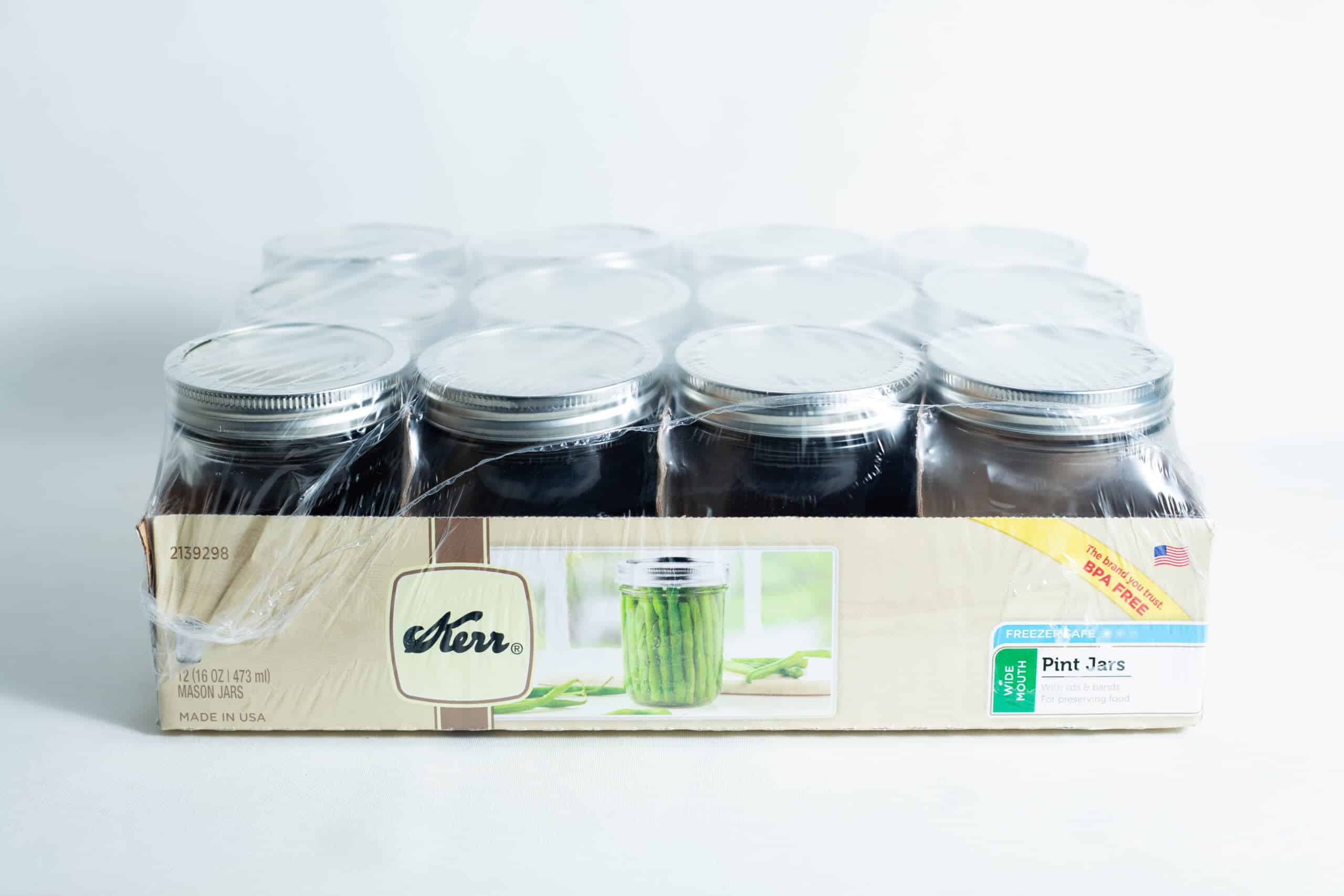 A sealed pack of twelve Kerr wide mouth Mason jar glass pint size 473ml with lids and bands, packed in a cardboard tray with plastic wrapping.