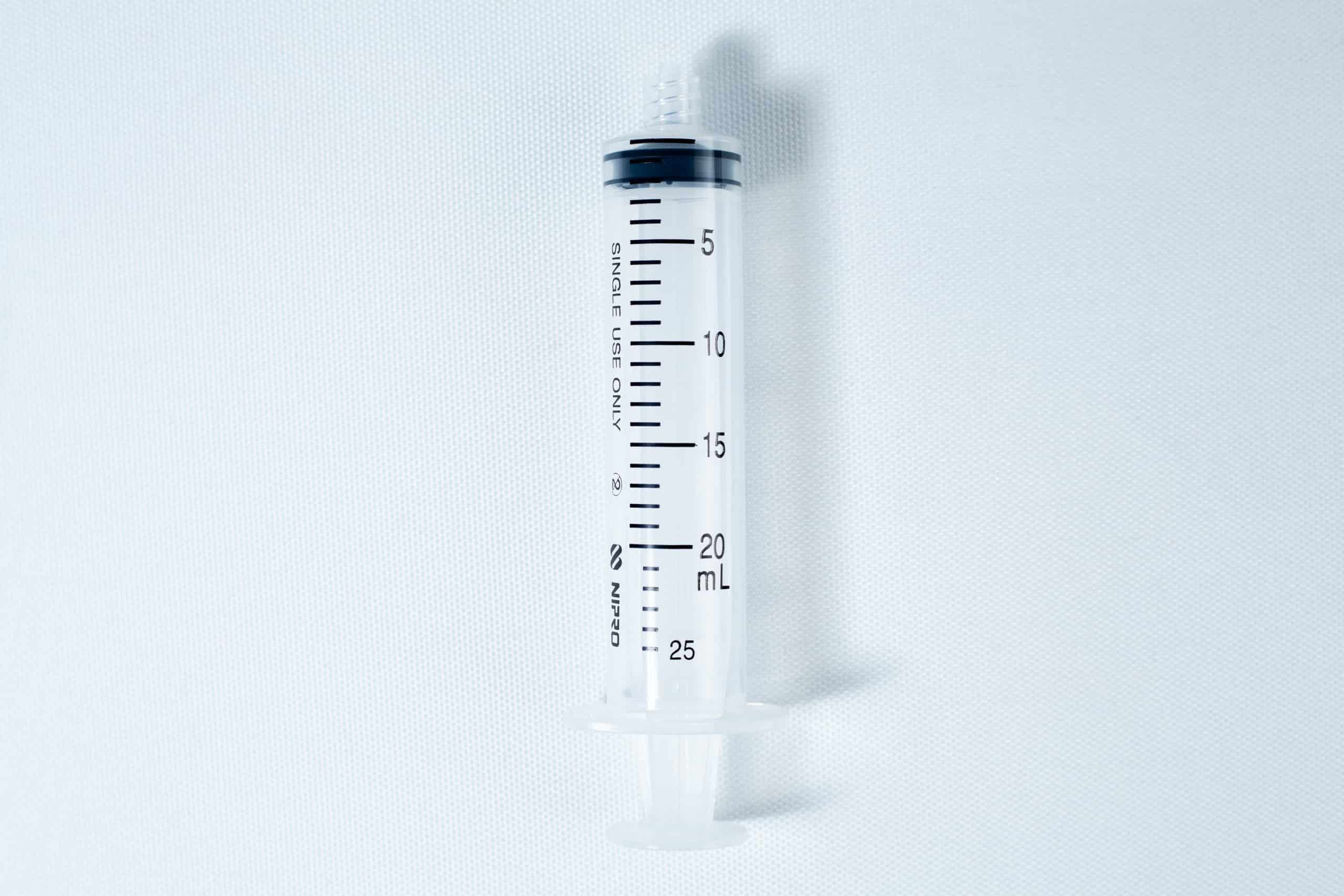 A clear, empty plastic syringe with black measurement markings up to 25 mL on a white background.