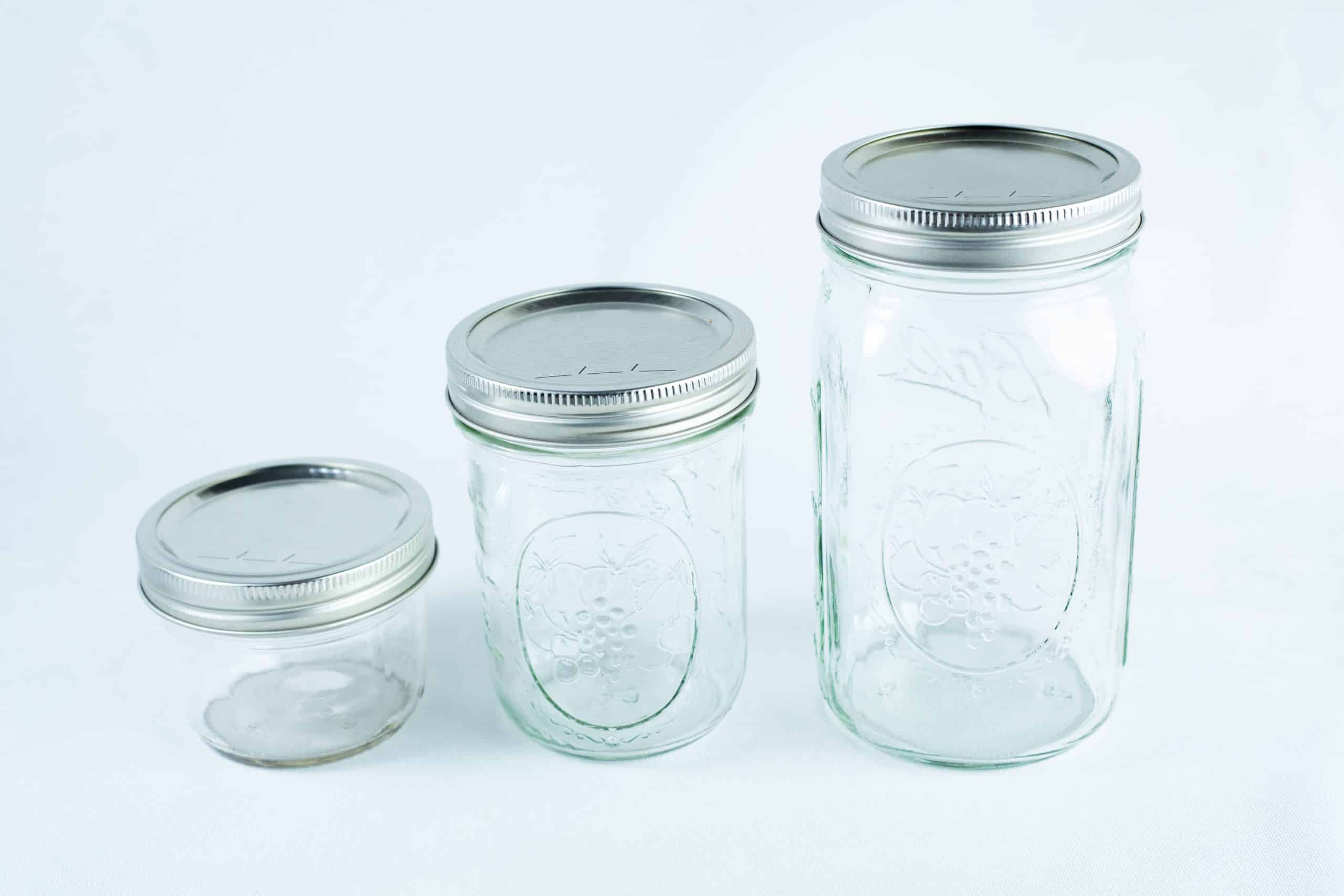 Three empty wide-mouthed glass Mason jars, each featuring an 86mm metal lid and band set, are arranged on a white background.