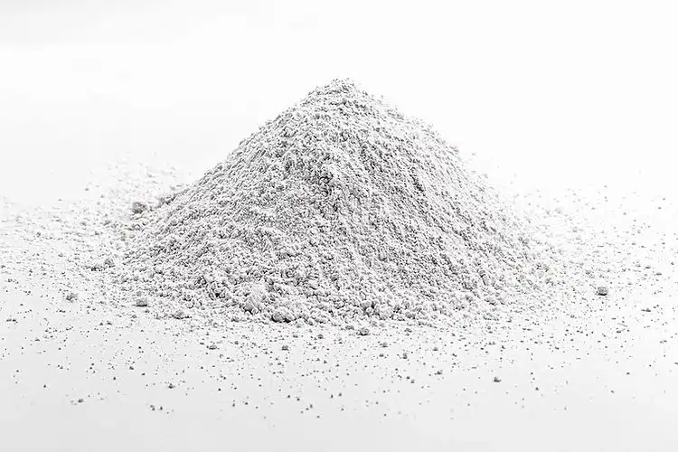 A small mound of Calcium Carbonate for Mycology, a fine white powder, is scattered on a plain white surface.