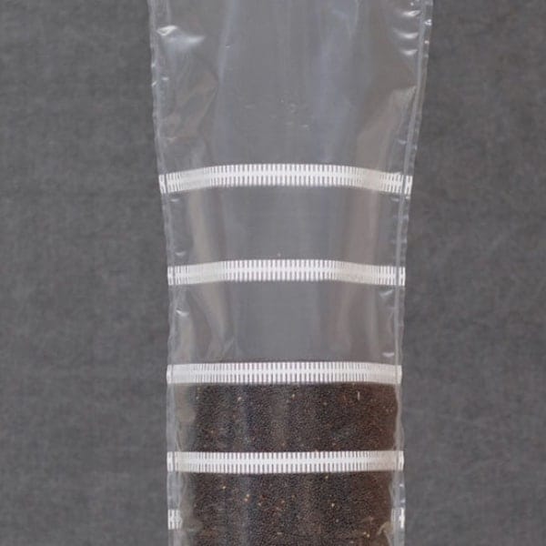 Grow bags Mushroom Sac O2 are clear plastic tubes, partially filled with dark soil and sealed in horizontal sections, ensuring optimal conditions for mushroom cultivation.