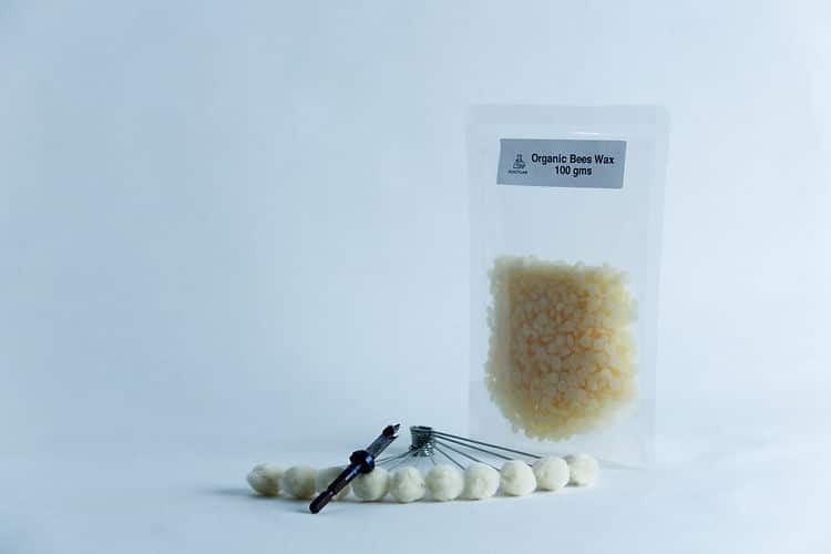 A packet of organic beeswax and a tool with white beads, ideal for your Mushroom Log Kit | Mushroom Inoculation Kit (Log Dowel), displayed on a clean white background.