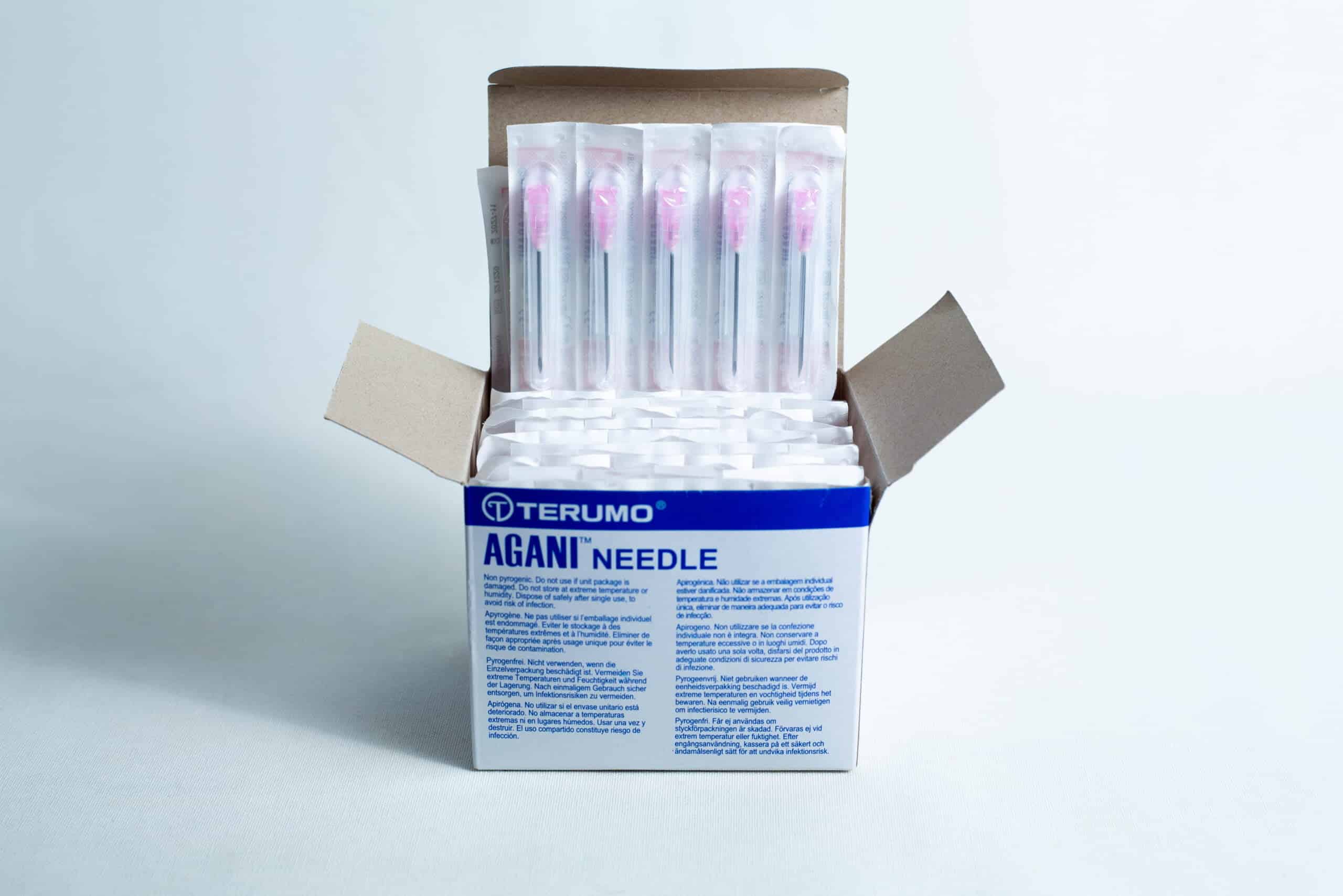 Open box of sterile 18G hypodermic needles whole box 100pcs, showing several individually wrapped sterile needles inside.