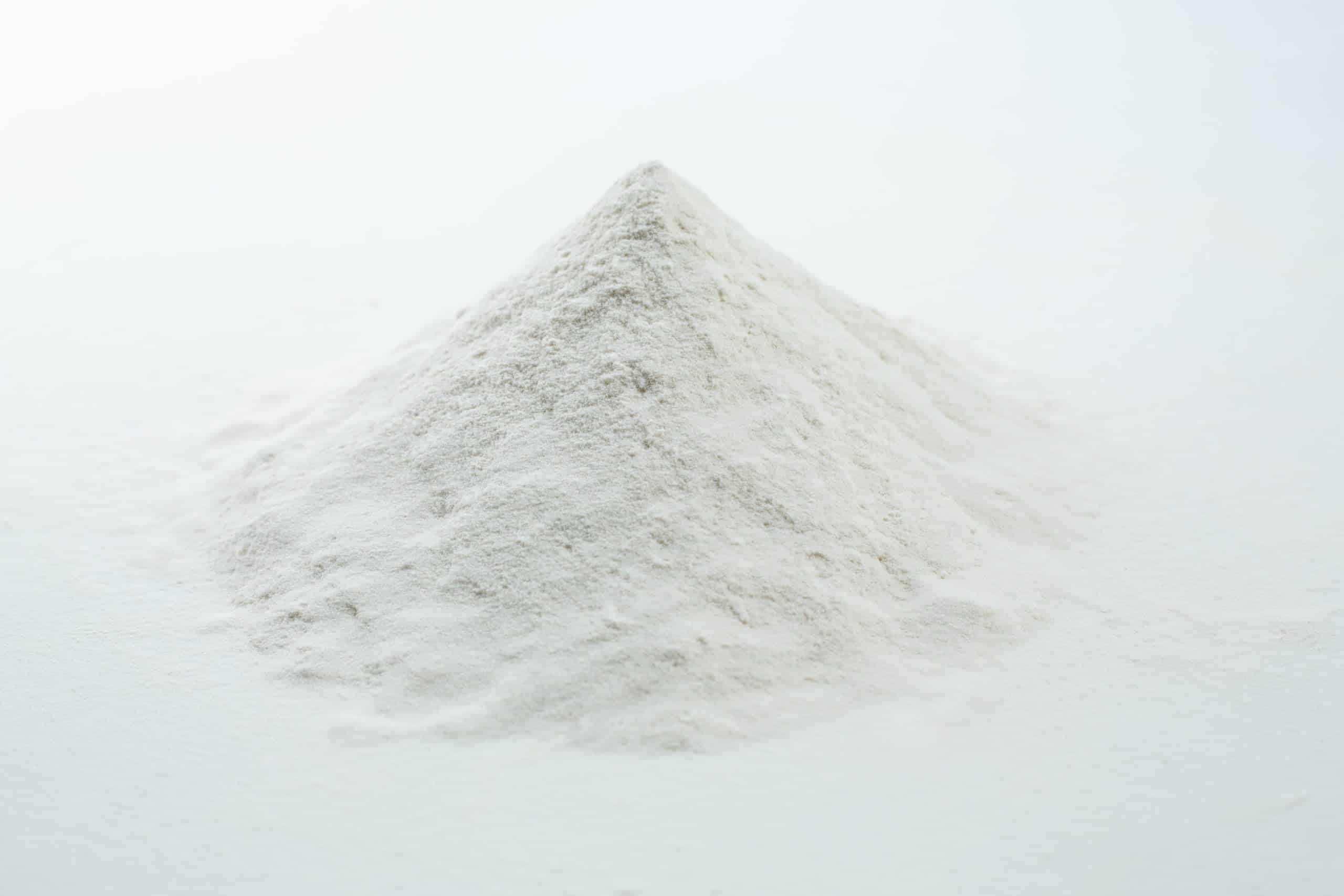 A small mound of fine white powder on a plain white surface, resembling Agar Mix MYAG Antibacterial Malt Extract Yeast used for culturing microbes.