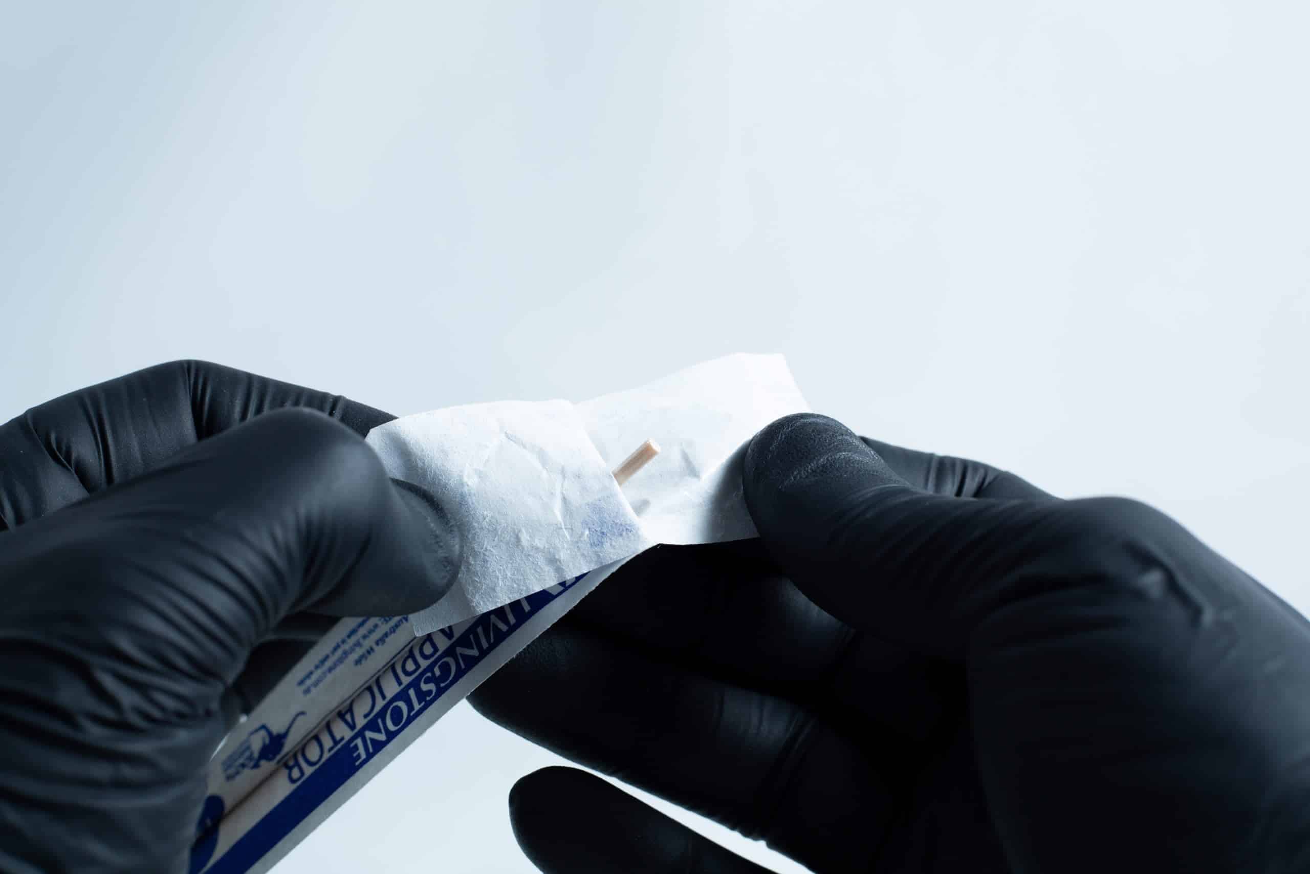Gloved hands open an antiseptic wipe packet against a plain background, preparing the agar Petri dish MEA School Science Fun Project Kit for a school science activity.