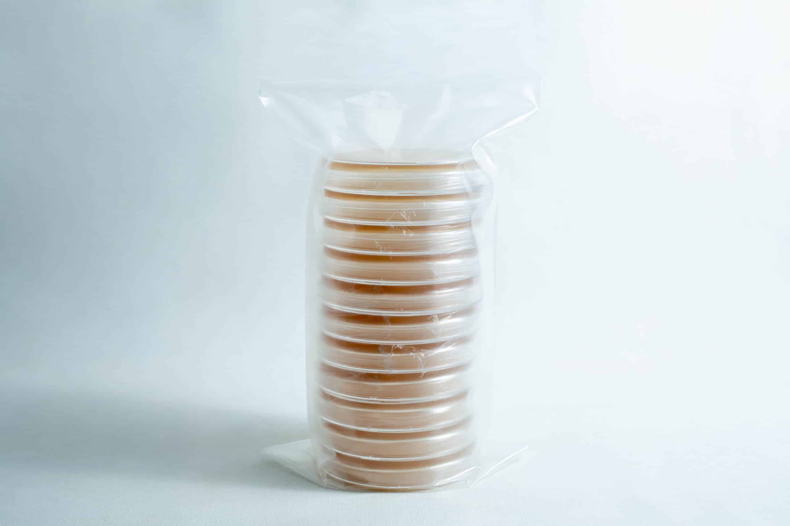 A stack of sealed Pre-poured MEAG Agar Plates (Antibacterial) 90mm, filled with agar and wrapped in clear plastic, displayed on a white background.