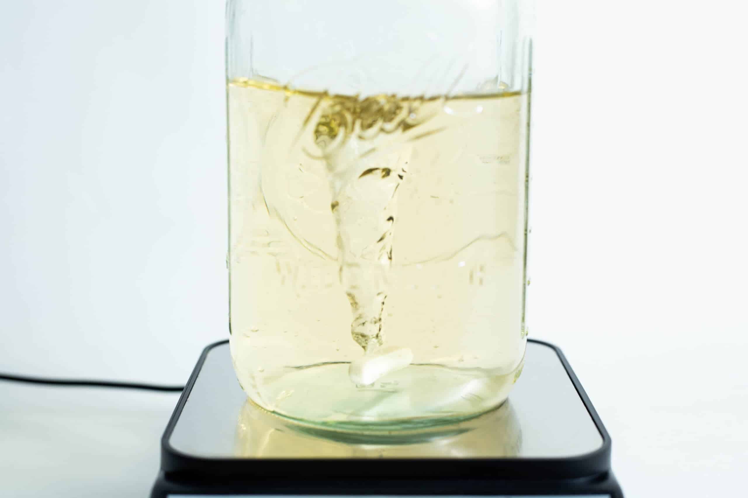 A vortex swirls in a yellow liquid within a glass jar on the Magnetic Stirrer Ciblanc 3500rpm, highlighting the stirring precision of this device.