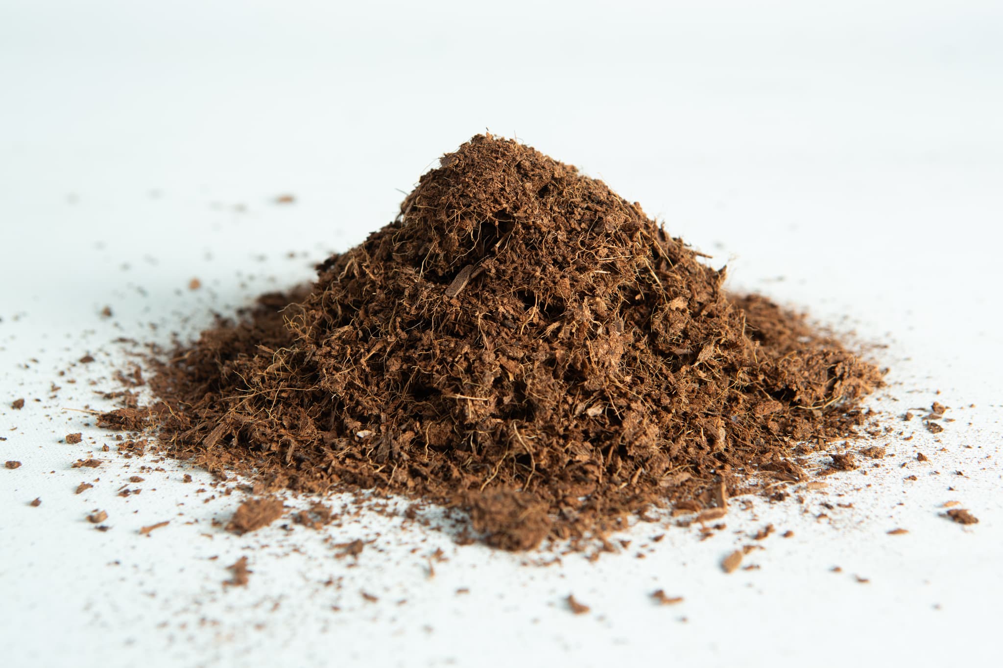 A small pile of coco coir block 5 kg, 60L, washed of salts buffered RHP grade on a white surface.