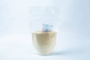 A transparent pouch of Liquid Culture Pre-mix | DLME | Now Extra Clear, containing light yellow dextrose and light malt extract powder, with a small silica gel sachet inside.