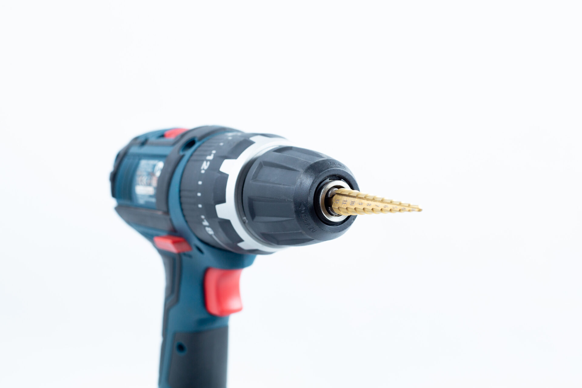 A Drill Bit for holes size 3mm-12mm Titanium Coated is attached to a cordless power drill, displayed against a white background.