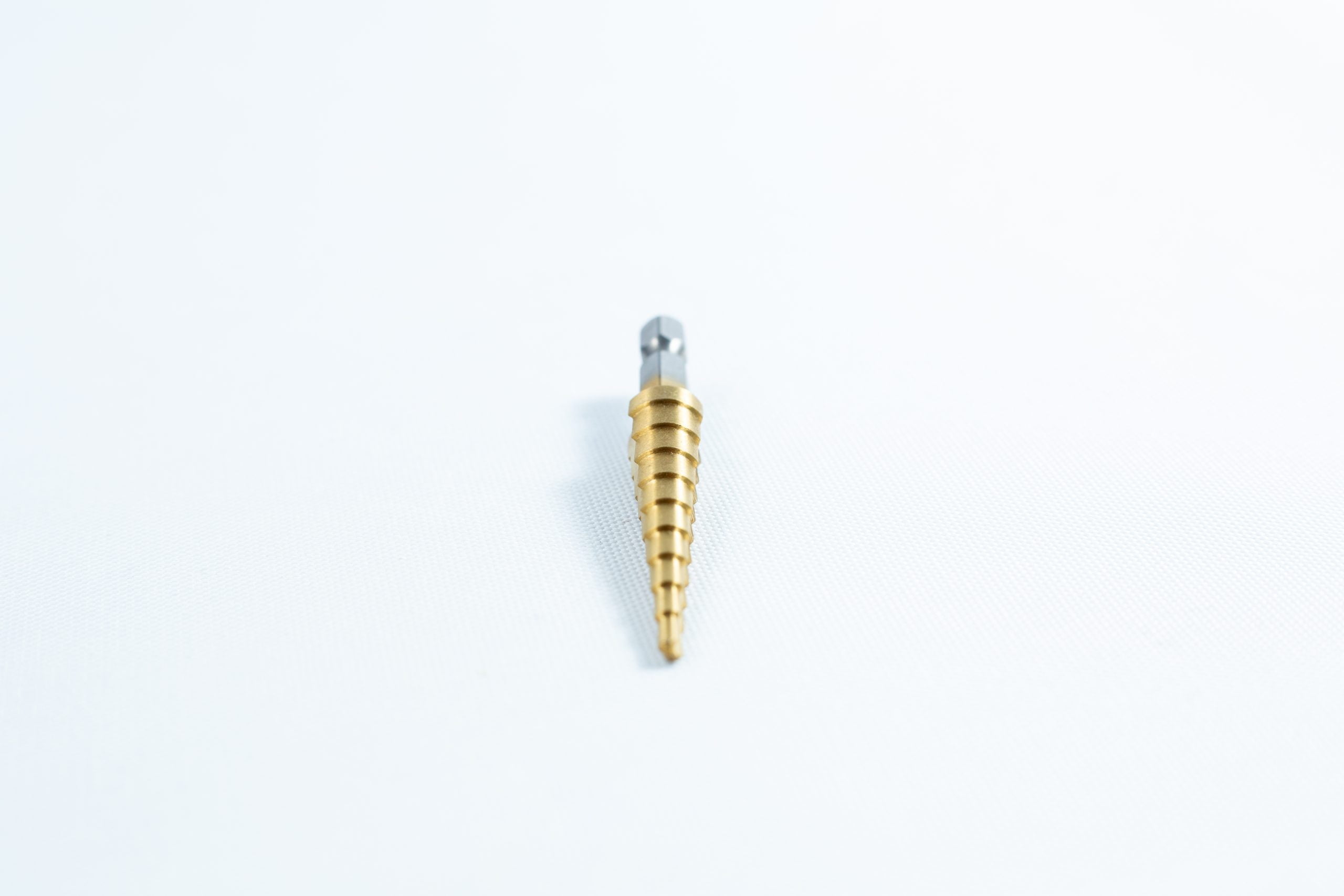 The "Drill Bit for holes size 3mm-12mm Titanium Coated" features a gold step design and silver shank, shown on a white background.