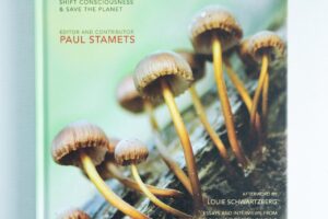 Book cover of Fantastic Fungi by Louie Schwartzberg, showing mushrooms sprouting from a log against a light background.