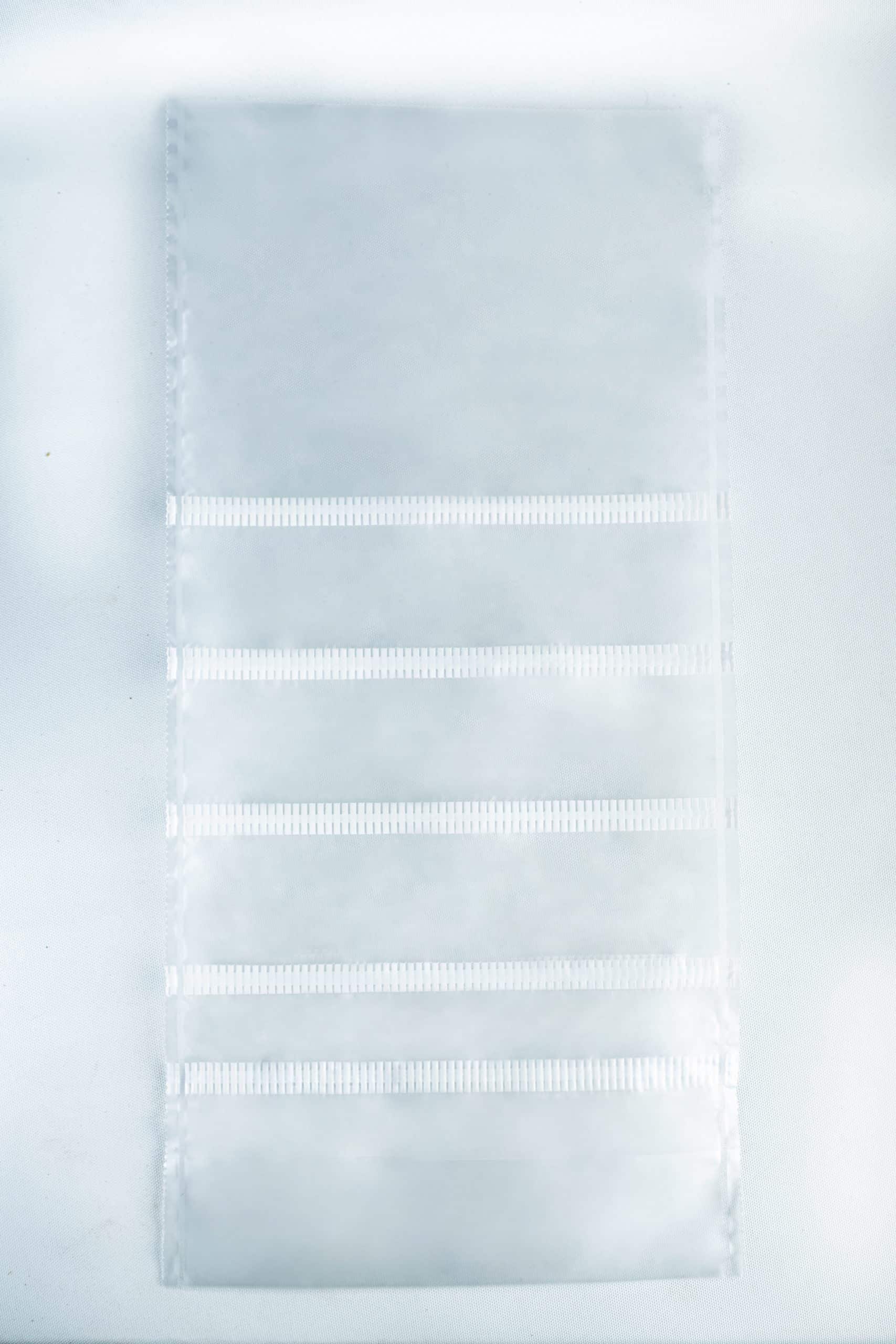 A clear plastic sheet with six horizontal pockets, ideal for organising your Mushroom Grow Bags Unicorn for spawn and substrate, set against a white background.
