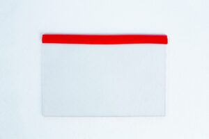 A transparent pocket with a red top edge on a white textured background is perfect for storing the Glass Spore Print Slides booklet (12.8cm x 8.5cm x 1mm) to safely preserve spore prints.