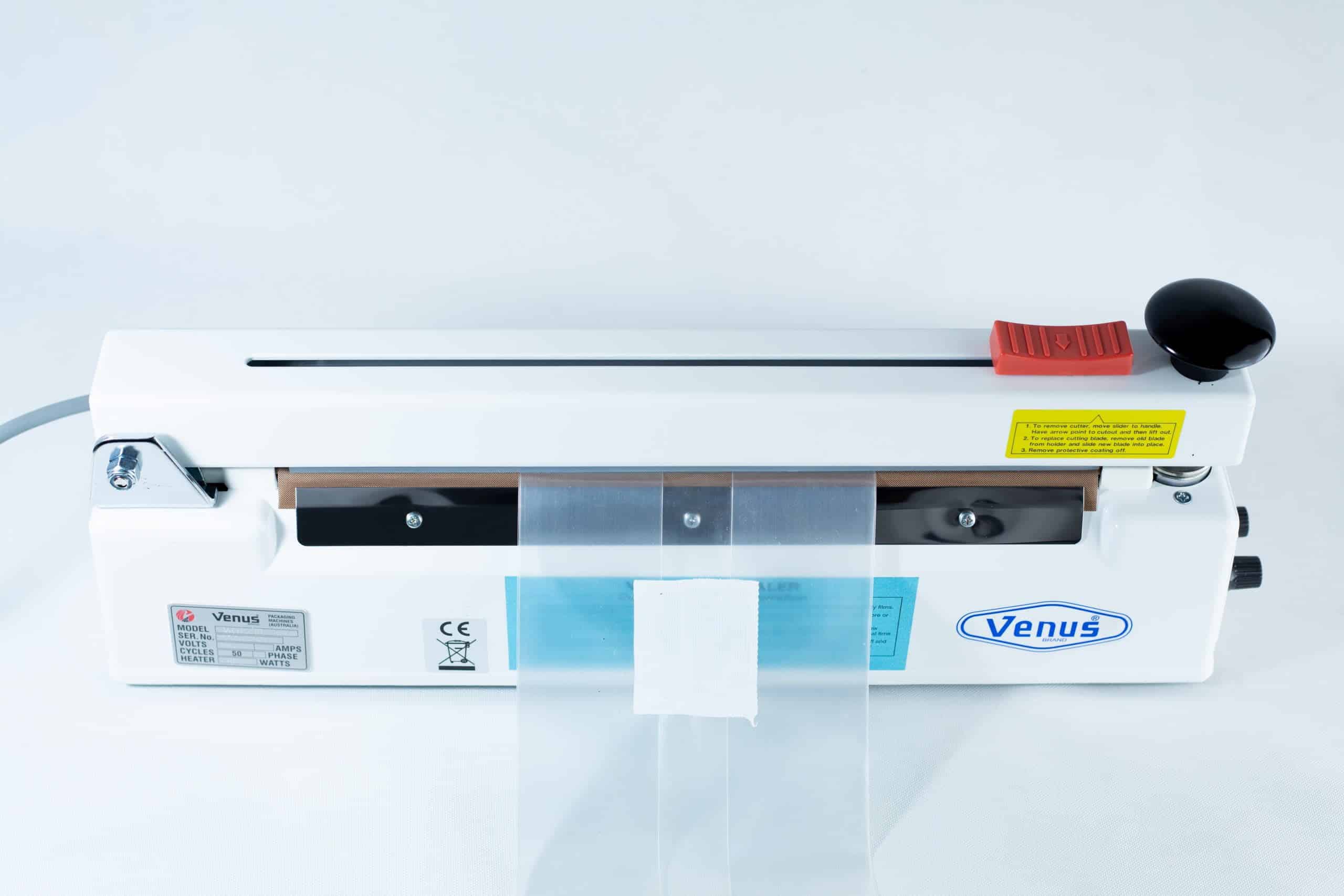 A Heat Sealer 30cm Seal Width 5mm with cutter and magnet in white is shown from above with a plastic bag placed in the sealing area.