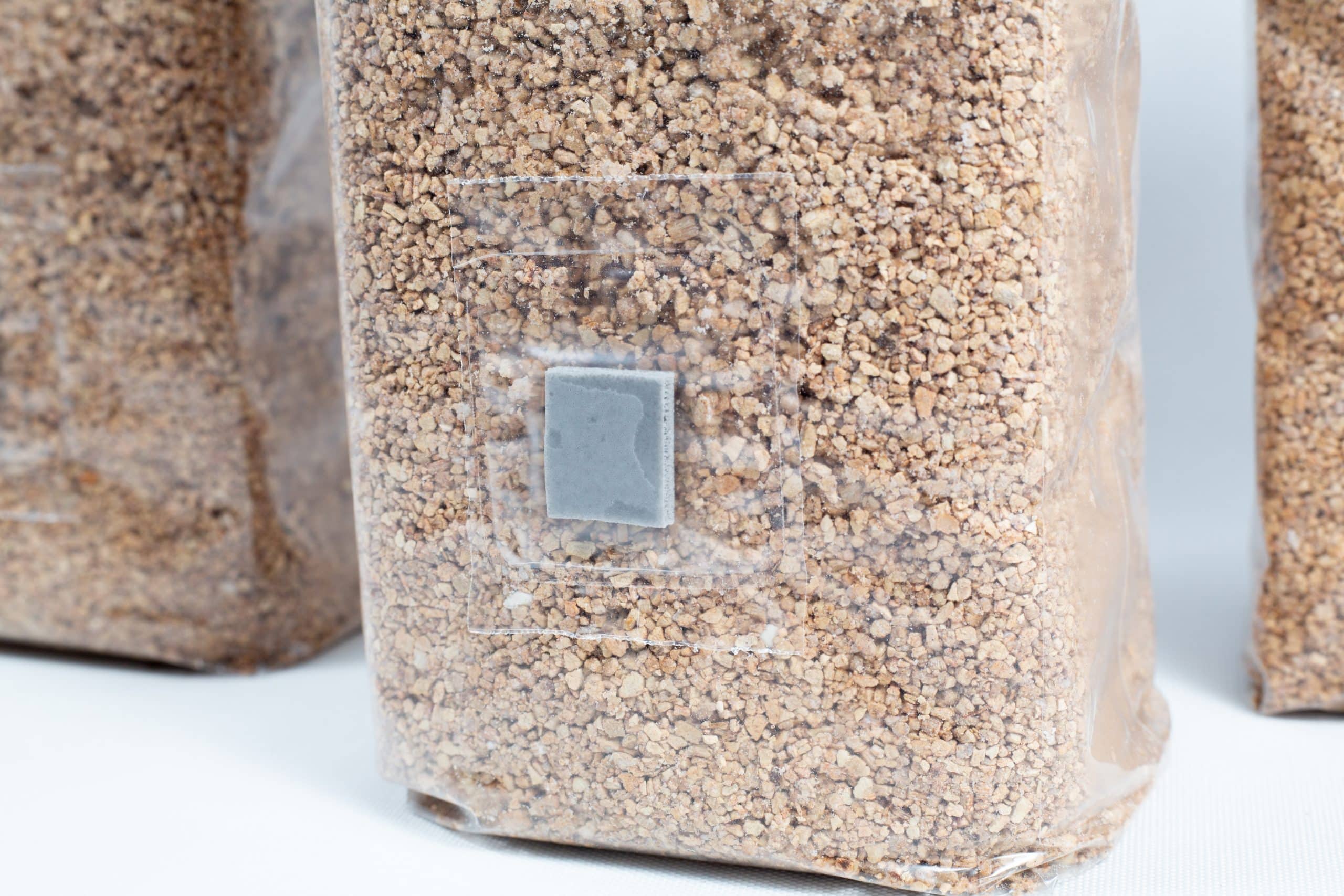 A clear bag of brown grains with a grey patch, ideal for mushroom substrates—perfect for PF Tek using 3×1kg Organic Brown Rice Flour (BRF) & Vermiculite bags.
