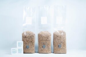 Three 1kg Organic Brown Rice Flour (BRF) & Vermiculite bags for PF Tek sit beside two silica gel sachets on a white background.