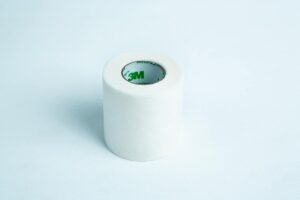 A roll of Micropore tape Mycology autoclavable breathable rests on a light blue background, ready for gentle and secure medical use.
