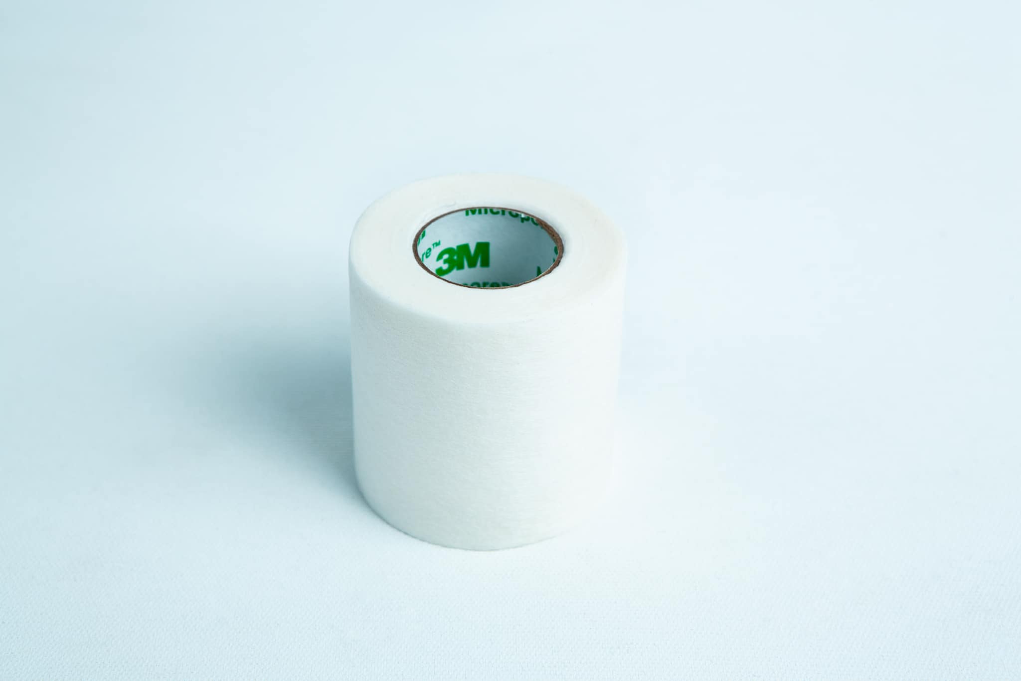 A roll of Micropore tape Mycology autoclavable breathable rests on a light blue background, ready for gentle and secure medical use.