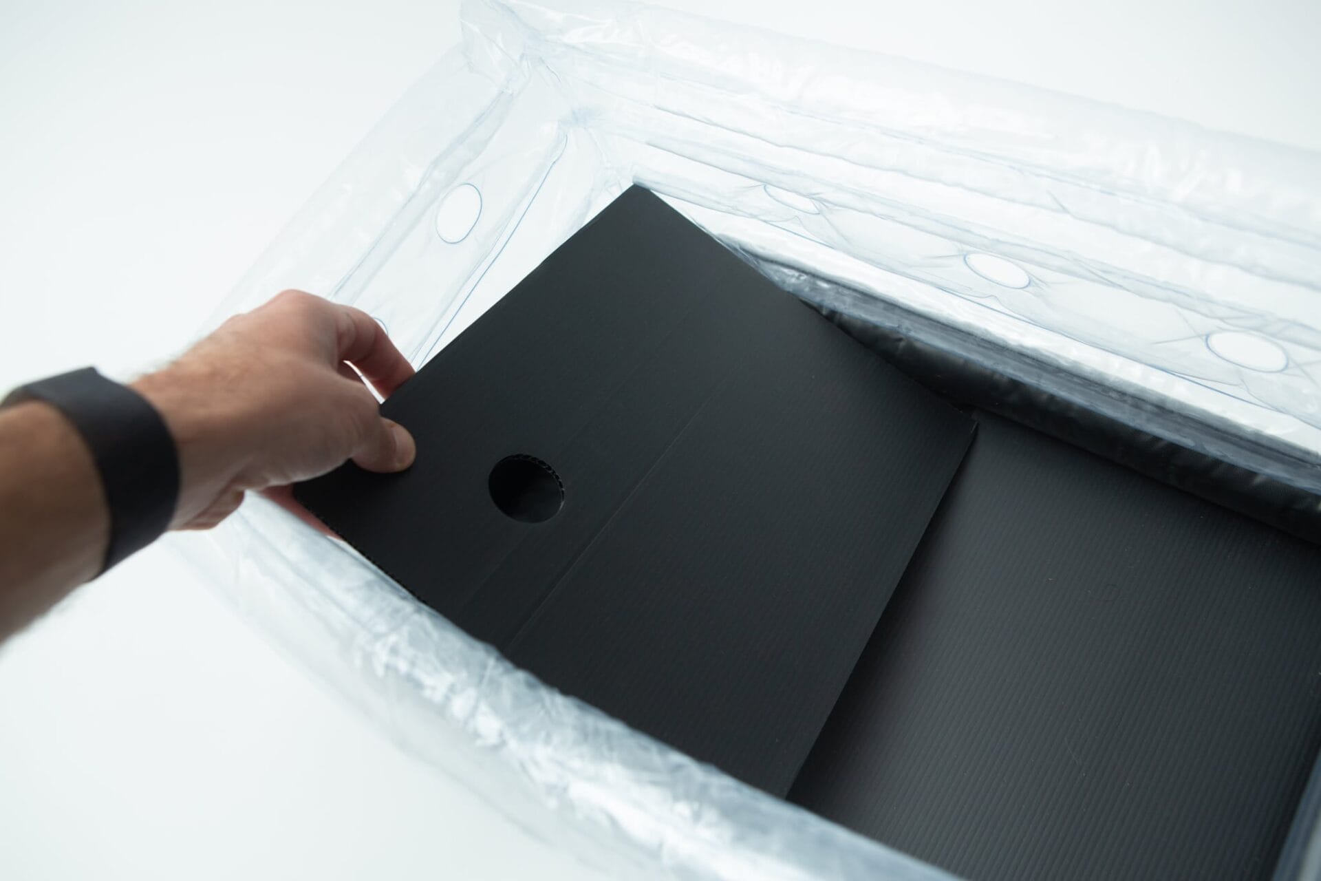 A hand places a black sheet with a hole into the Boomer Shroomer V 2.0 inflatable monotub kit for growing mushrooms.
