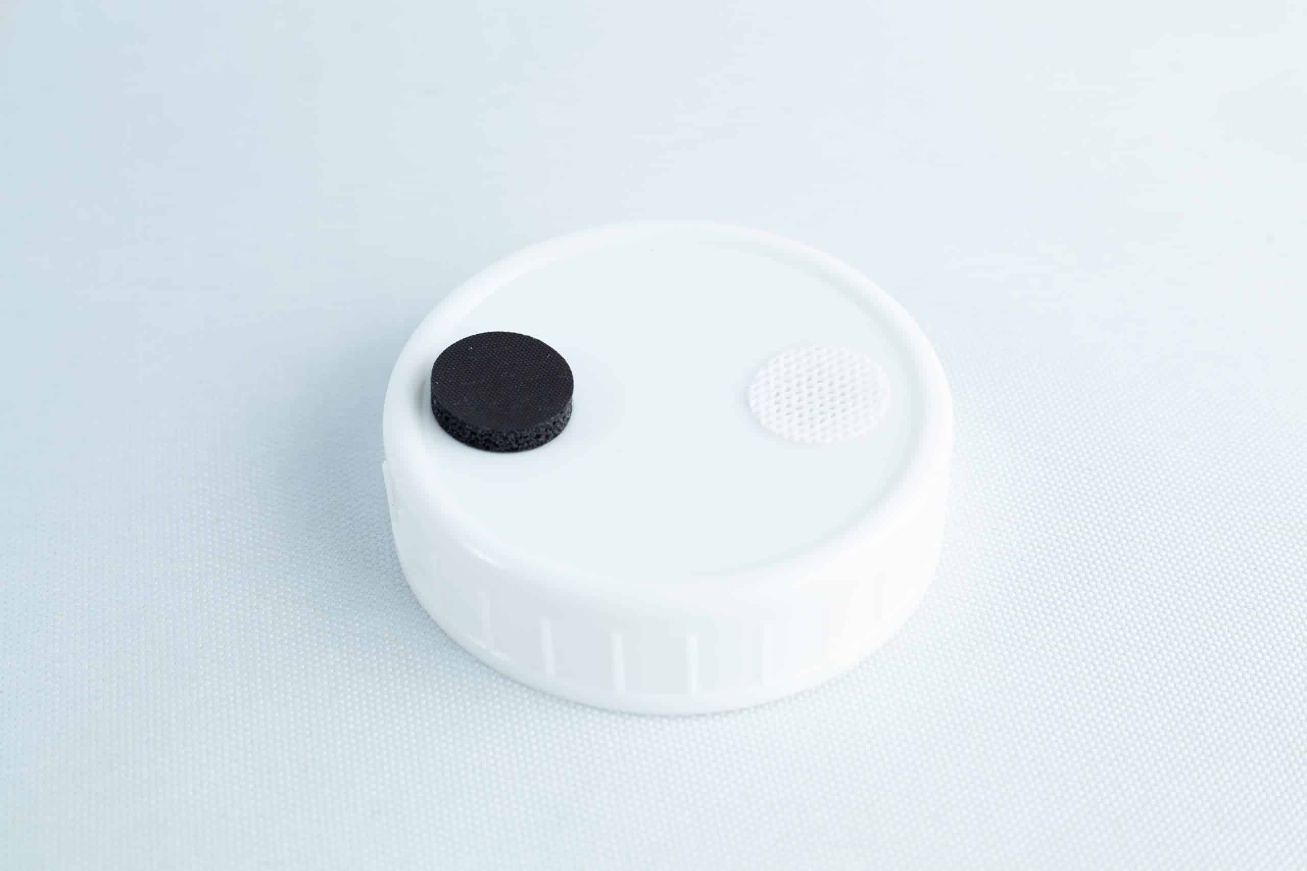 The Self-healing injection port & Air Vent Filter-3M features a white plastic cap with a black circle and textured white circle on top, designed for secure injections and air venting. Shown against a light background.