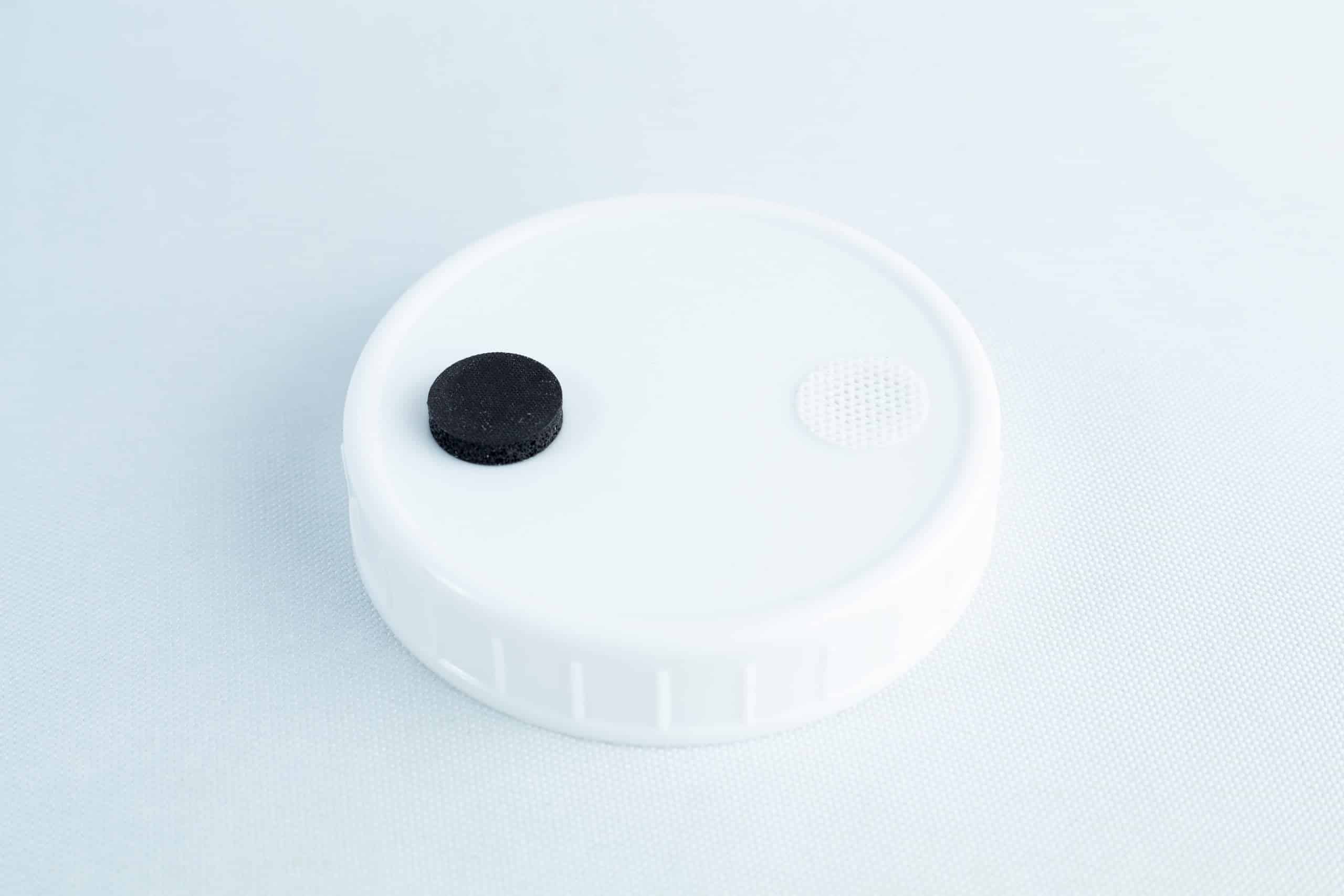 The Self-healing injection port & Air Vent Filter-3M is a white plastic lid with a black self-healing injection port and a small white air vent filter on top, shown against a light background.