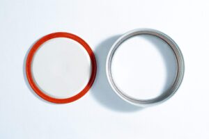The Self-healing injection port & Air Vent Filter-3M, with a metal ring, are displayed side by side on a white surface.