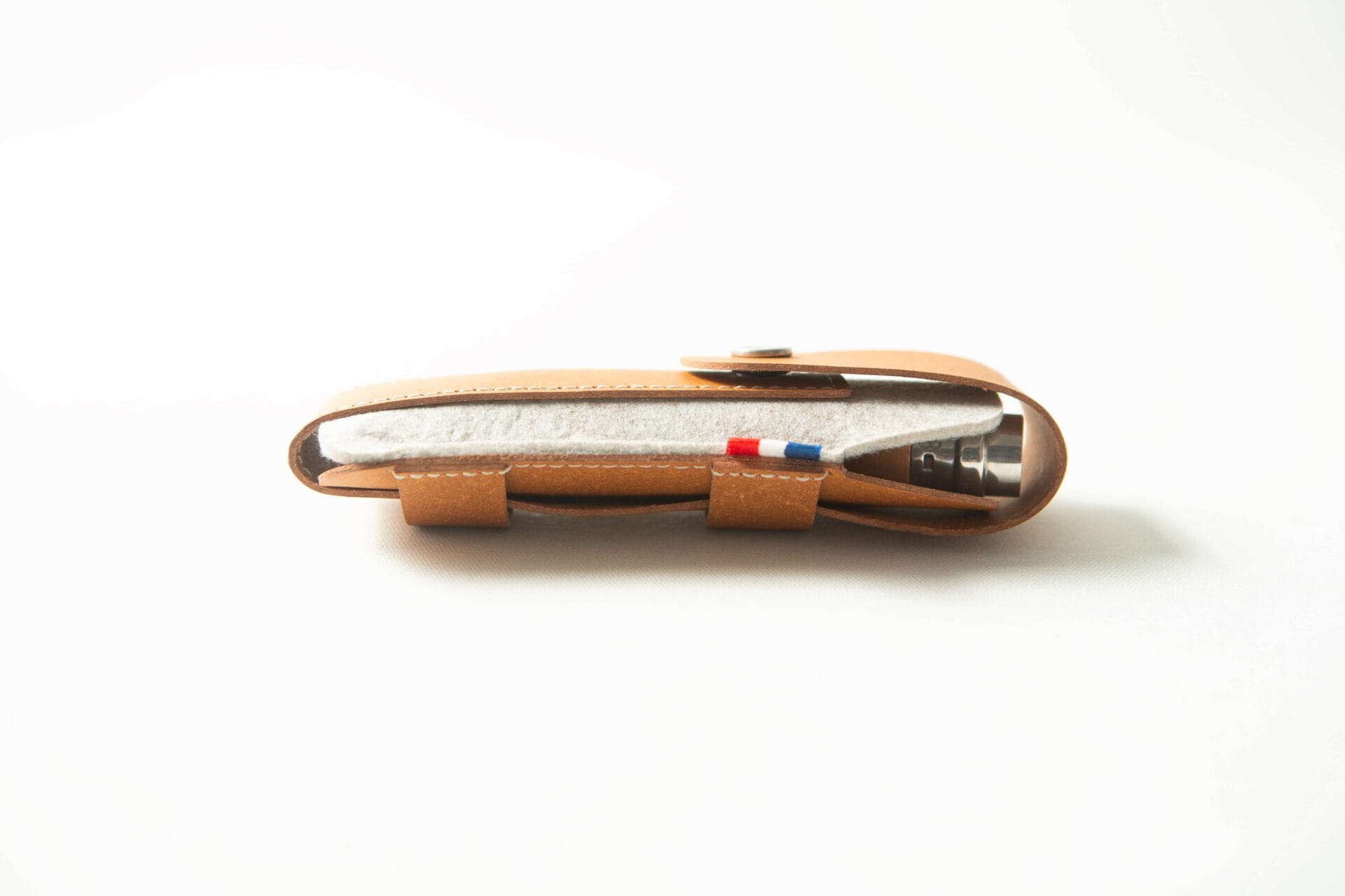 A brown Opinel Sheath - Brown leather pen case with a grey fabric pouch and a pen inside, shown on a white background.