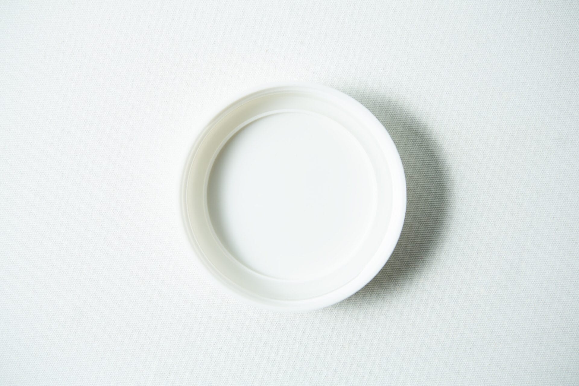 A Mason Jar Lid (Plain White Plastic, Wide Mouth 86mm) from "Mason Jar Lids" rests on a lightly textured surface, viewed from above.