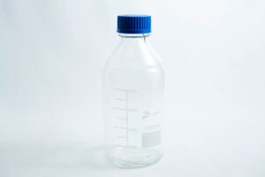 A Reagent bottle 1000ml made of clear glass with measurement markings and a blue screw cap.