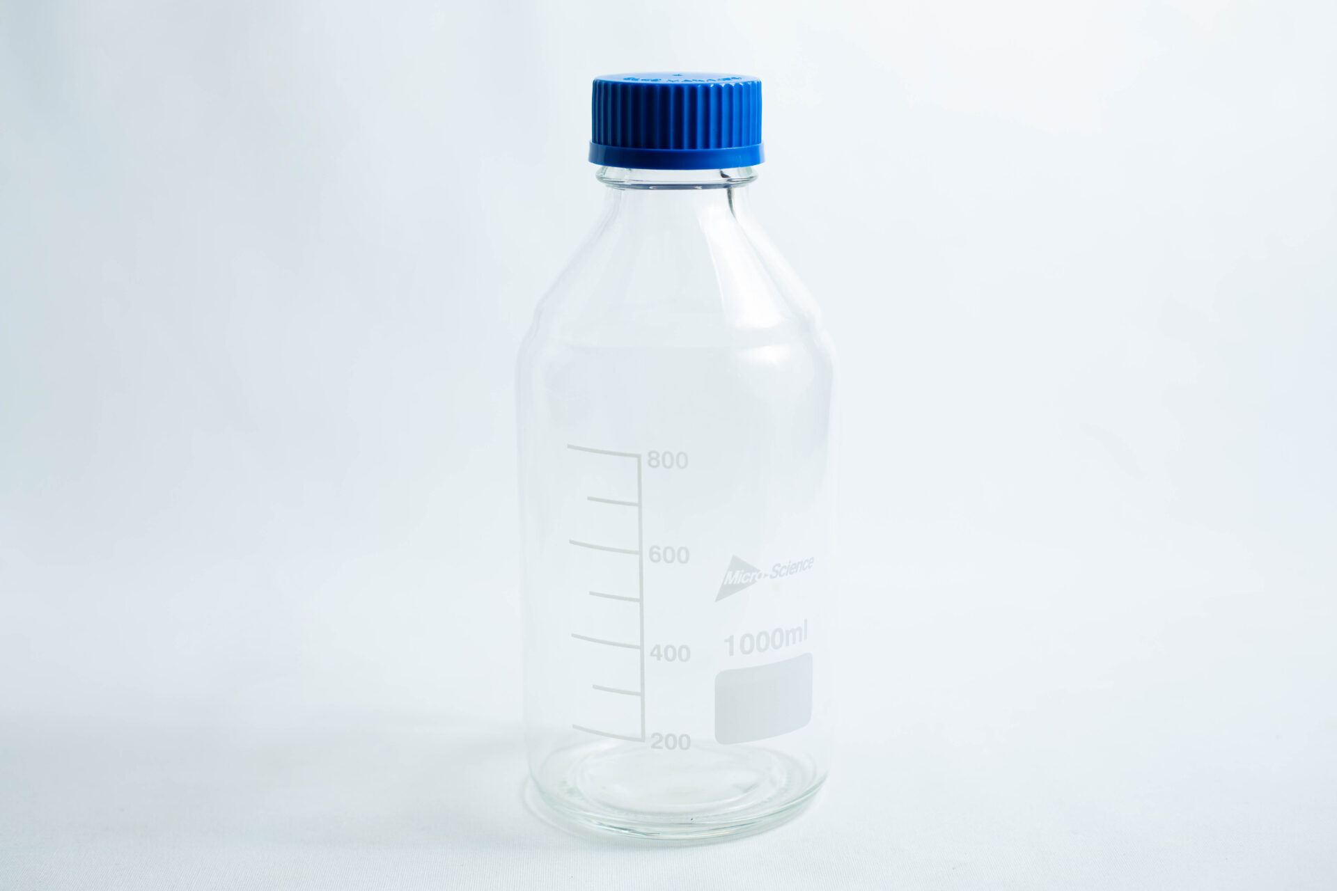 A Reagent bottle 1000ml made of clear glass with measurement markings and a blue screw cap.