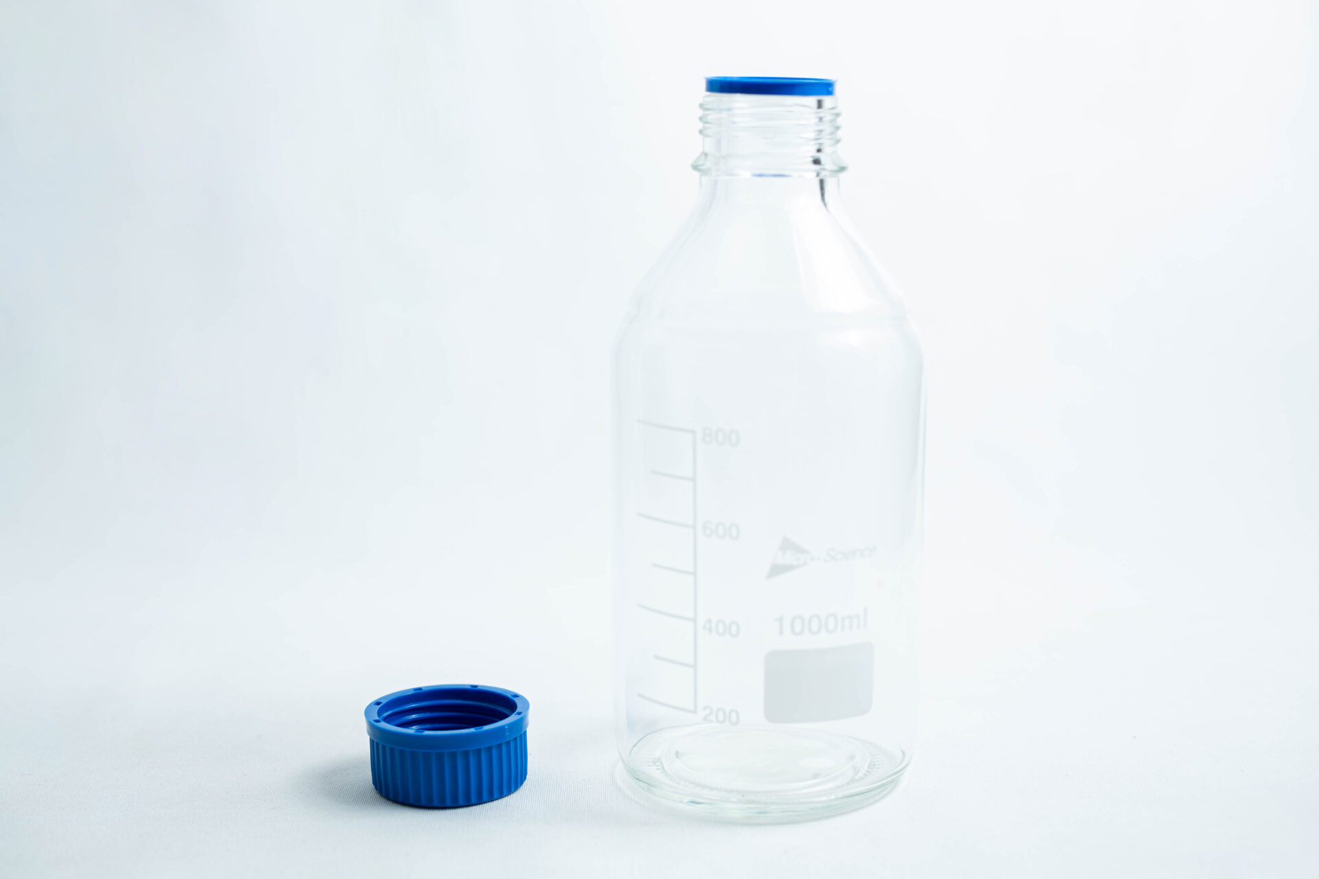 A clear reagent bottle 500ml / 1000ml with measurement lines and a blue cap beside it.