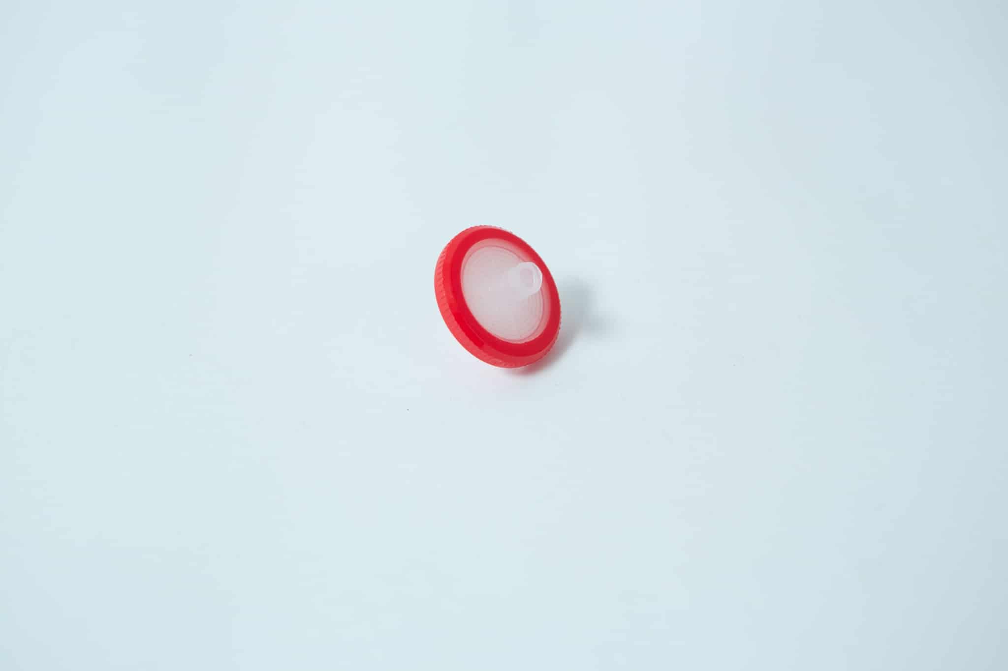 The Rubber Self-Healing Injection Port and Syringe Filter PTFE for Mycology, featuring a round red plastic body with a white centre and injection port, is displayed on a plain white background.