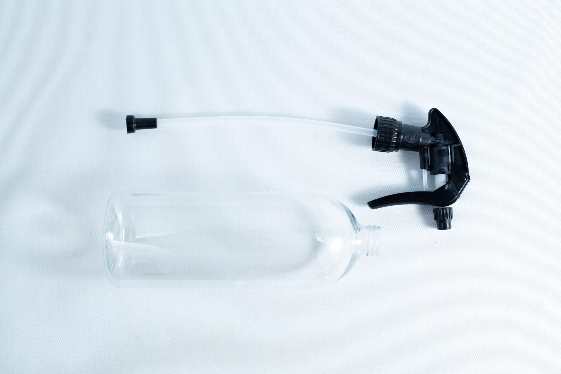 The Spray bottle Chemical resistant 1 Litre Heavy Duty, with a detached black nozzle, rests on a white surface—an ideal choice for safely handling various chemical solutions.