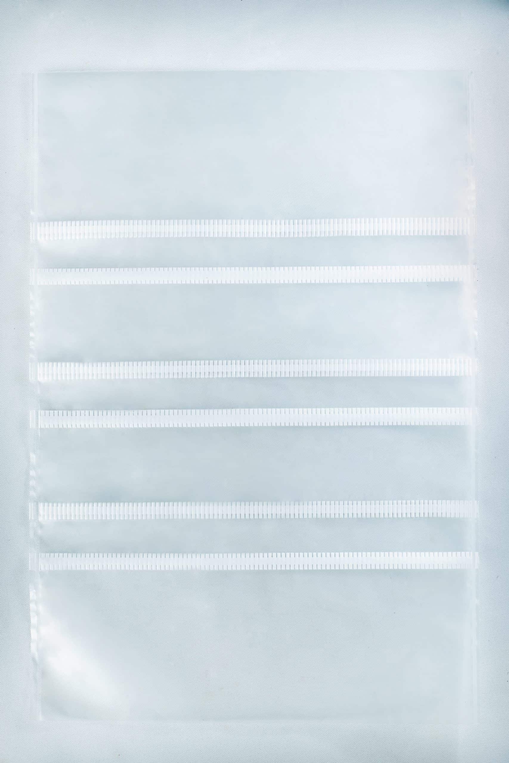 A clear plastic sheet with four horizontal pocket strips, perfect for organising supplies like Mushroom Grow Bags Unicorn for spawn and substrate or other mushroom grow bag essentials.