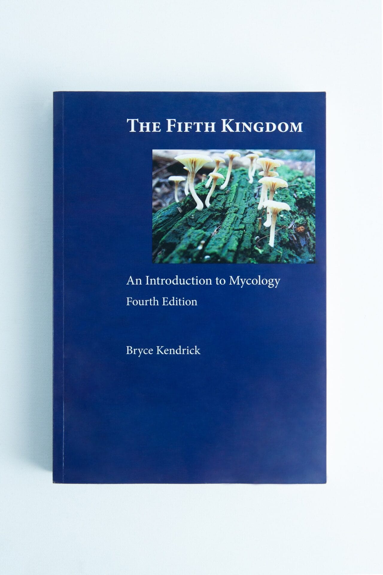 Blue book cover of "The Fifth Kingdom: Book by Bryce Kendrick," a renowned mycology title, featuring mushrooms on a log at the top.