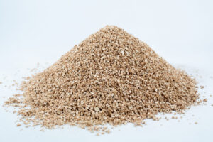 A mound of vermiculite, grade 2, fine, mycology rests on a white surface.