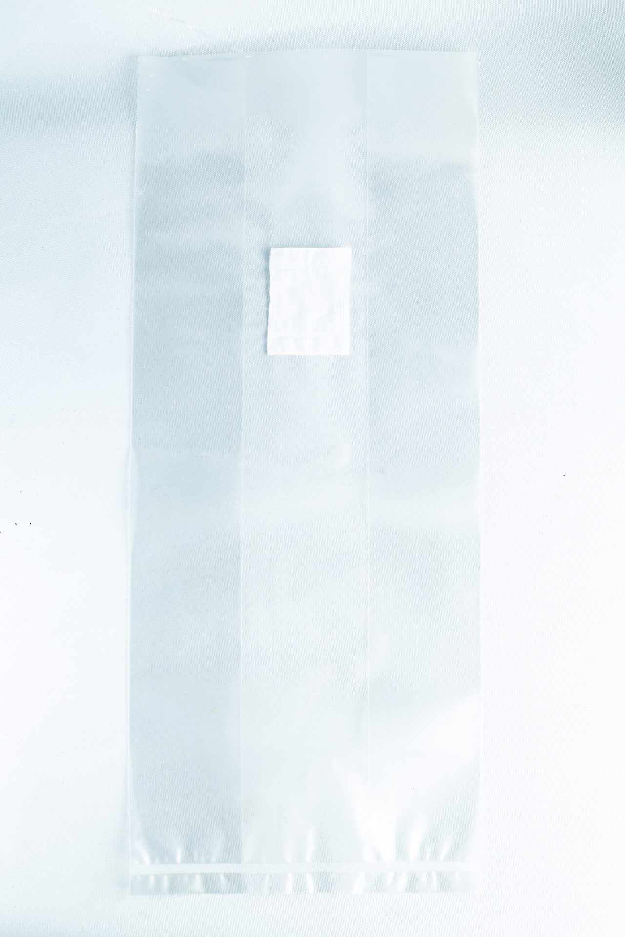 A small white square sits on a large transparent sheet made of material used in Mushroom Grow Bags Unicorn for spawn and substrate, all placed on a white background.