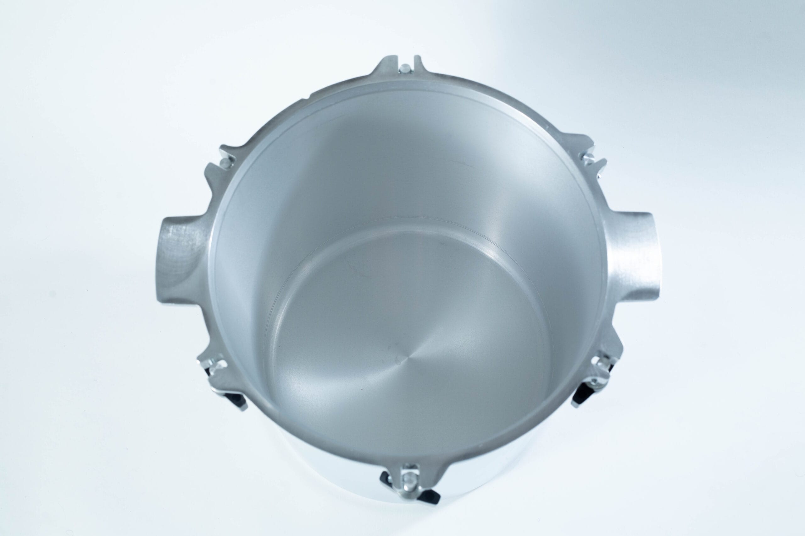 Top view of an empty, silver aluminium pressure cooker pot on a white background.