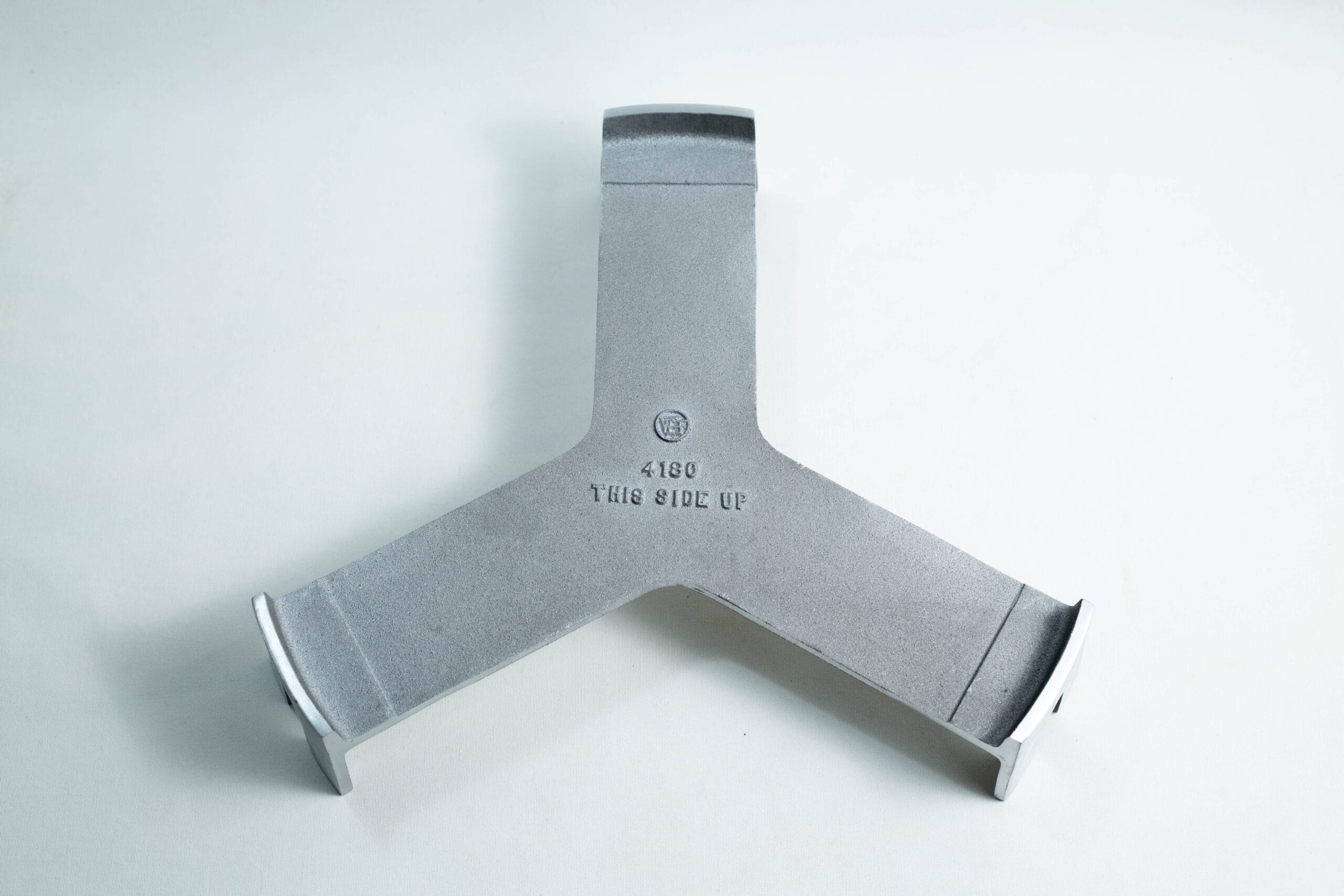 Grey metal Y-shaped object with THIS SIDE UP 4180 stamped in the centre, on a plain white background.