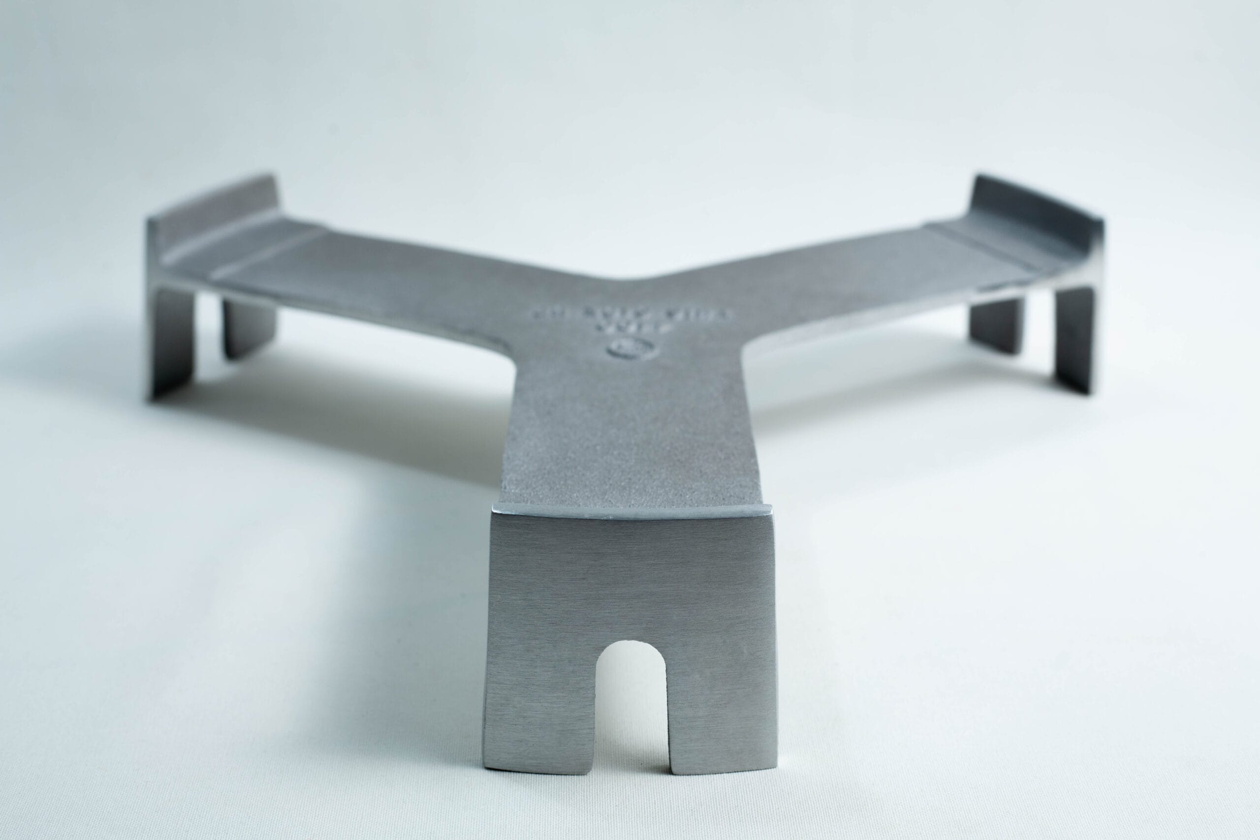 Metal trivet with three legs and a flat, Y-shaped design on a plain white background.