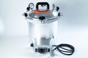 Silver pressure cooker with gauge, handle, power lead, and control knob on a white background.