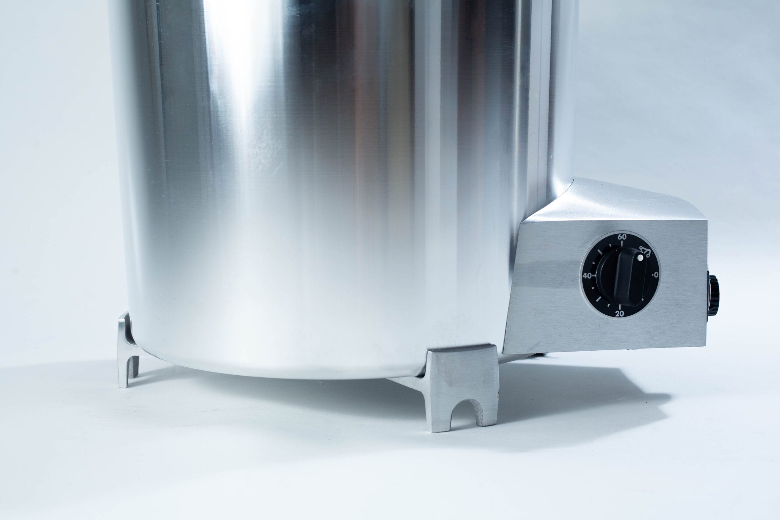 Close-up of a stainless steel appliance with a black dial on a grey base, set against a light background.
