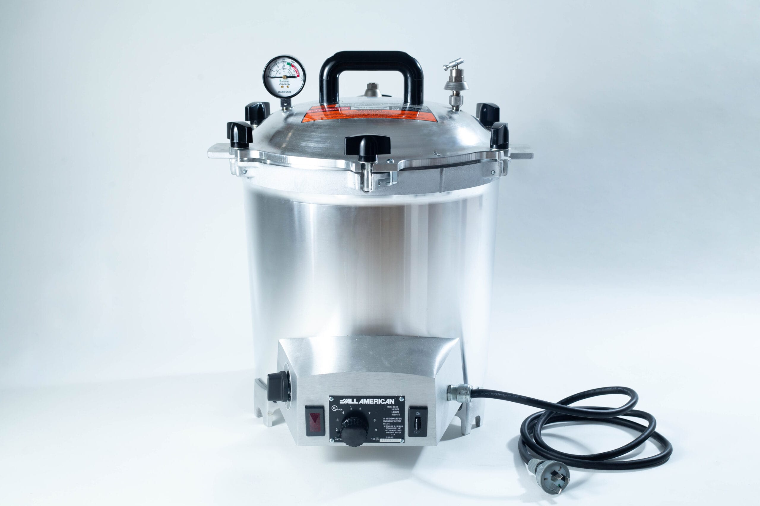 A silver electric pressure cooker with a gauge, black handle, knobs, and a power lead on a white background.