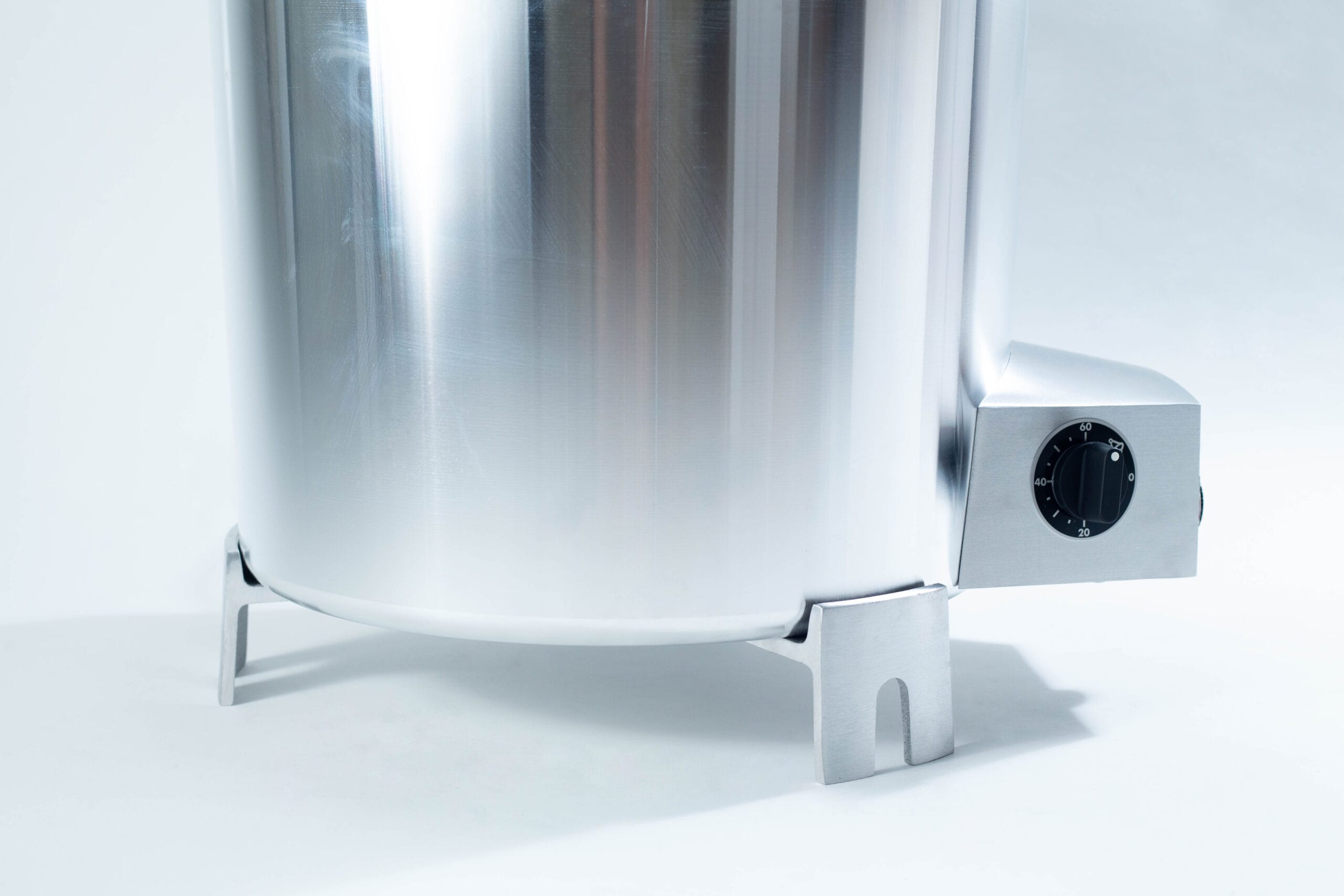 Close-up of a shiny stainless steel appliance with a black dial, shown on a white background.