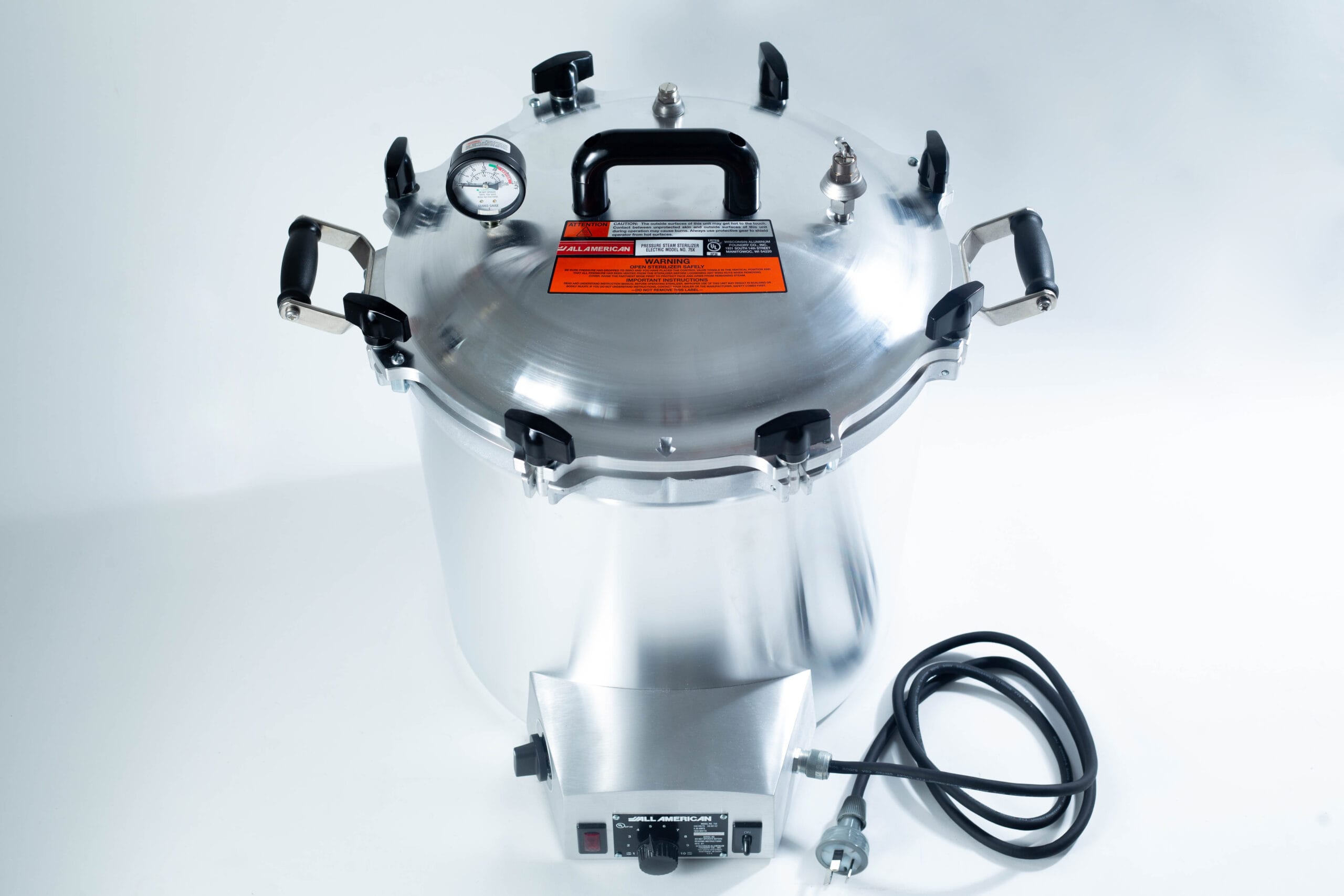 Large stainless steel pressure cooker with a gauge, black handles, and an attached power lead.
