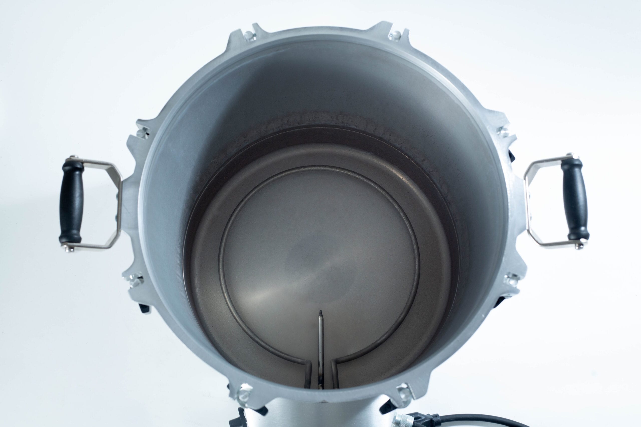 Top view of an empty metal brewing kettle with black handles on each side.