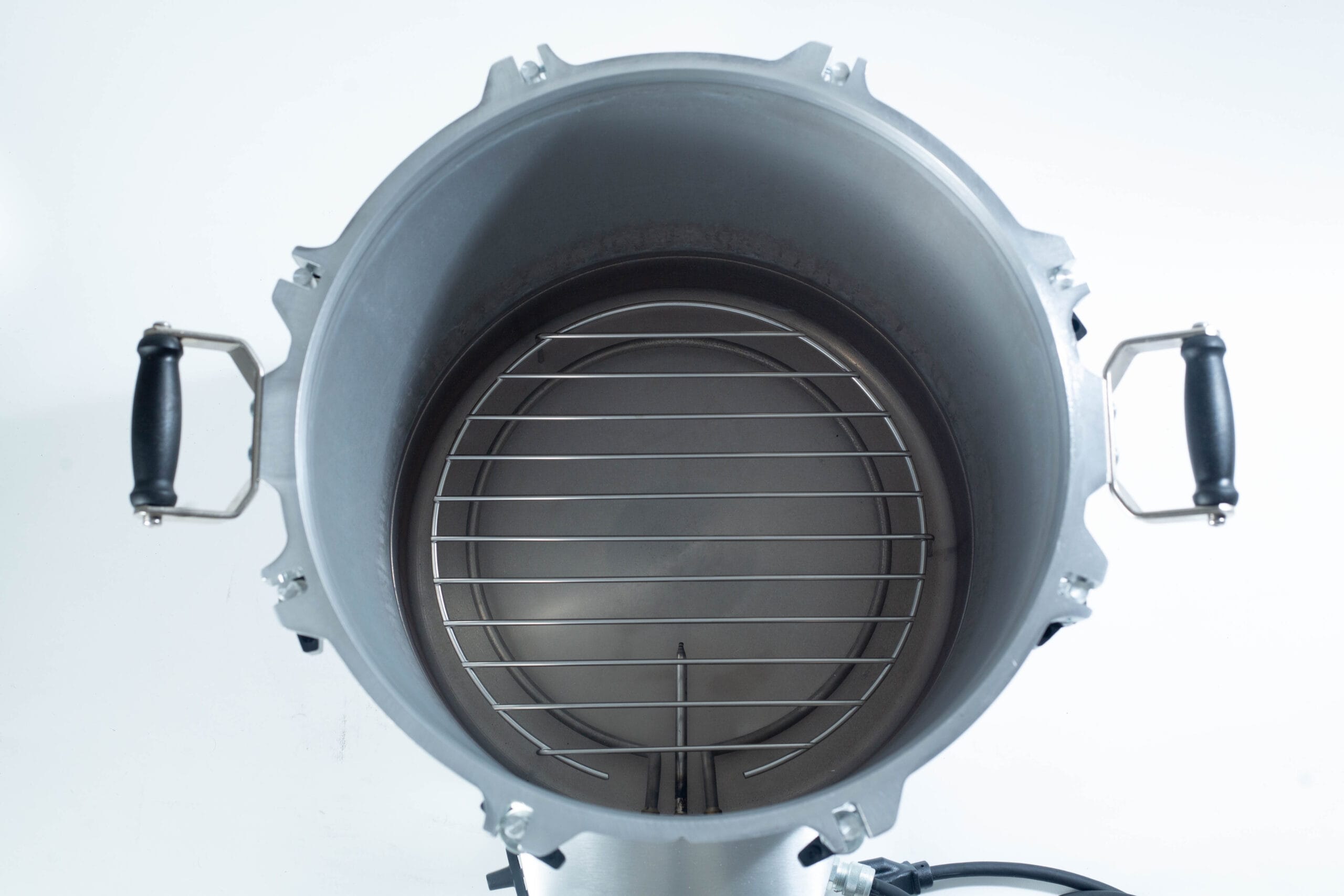 Top view of an empty metal pressure cooker with a round rack and side handles.